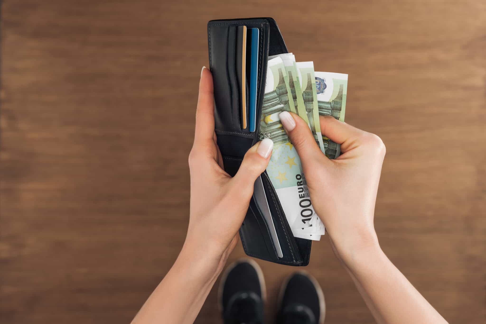 mulher a retirar da carteira várias notas de 100 euros a ilustrar Rendimentos que não pagam impostos no IRS