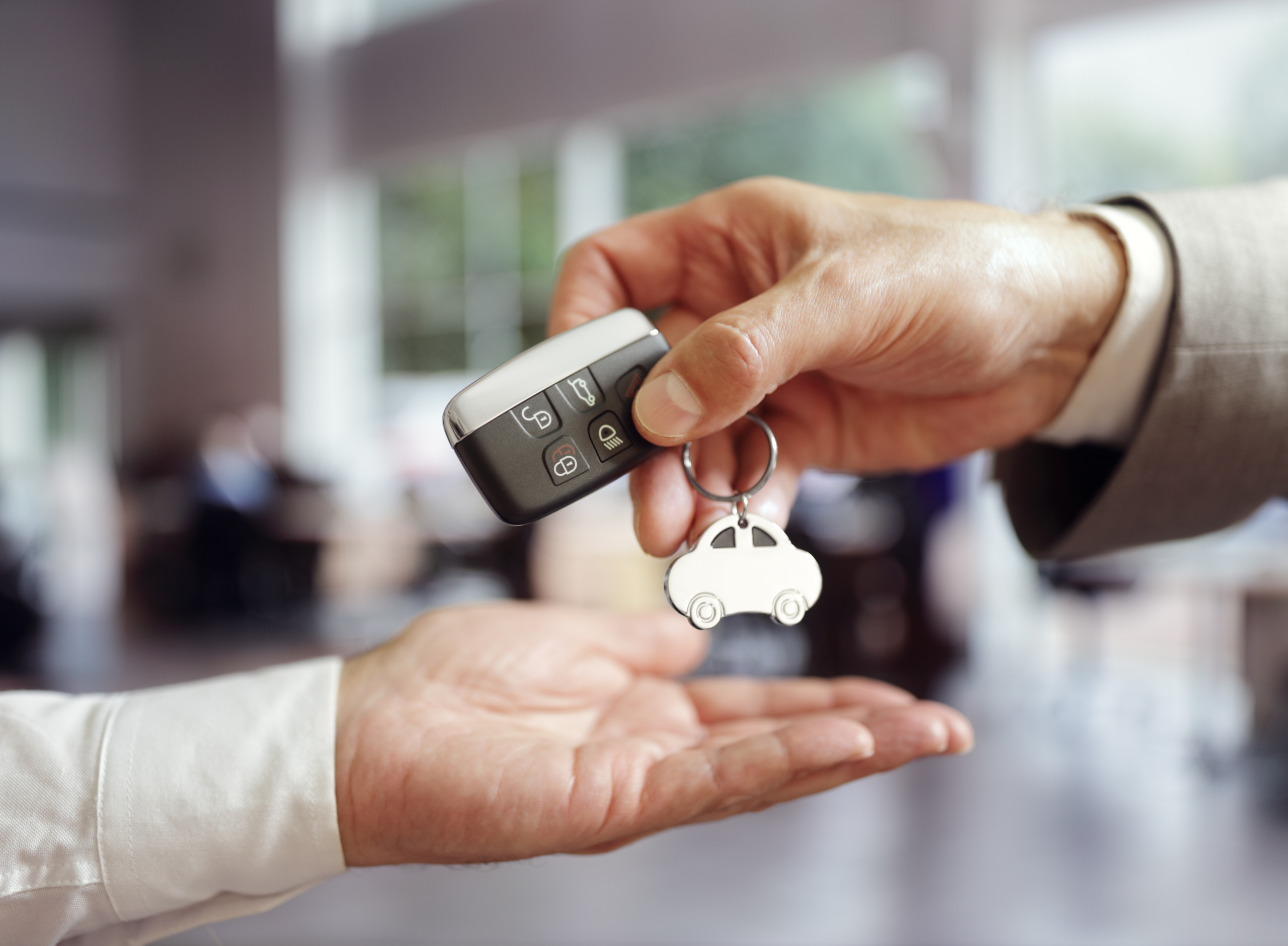 duas mãos de homens trocam a chave de um carro comprado recorrendo a uma das opões de financiamento, ou seja, Crédito automóvel, leasing ou renting