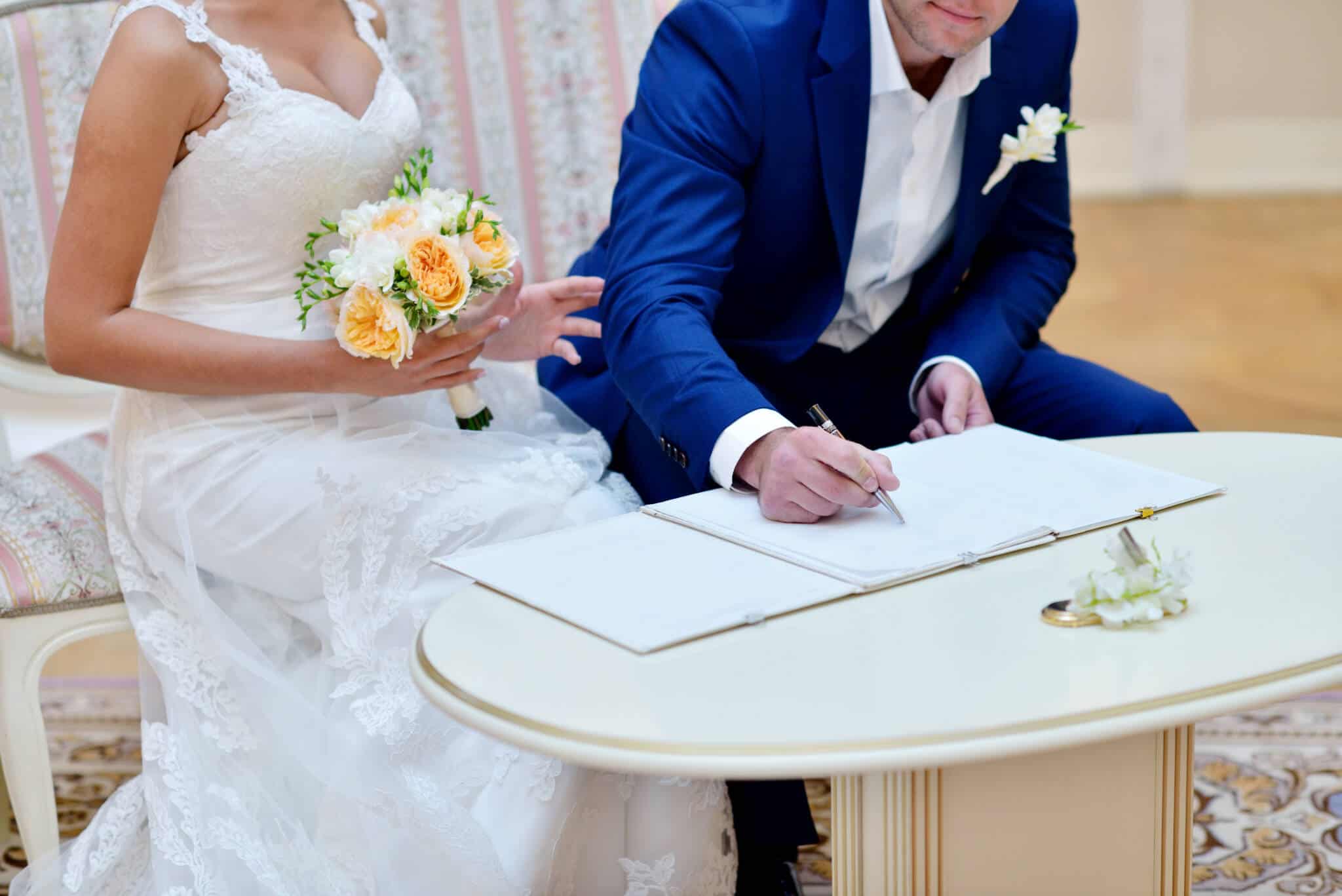 Casal vestido de noivos a assinar papéis de casamento