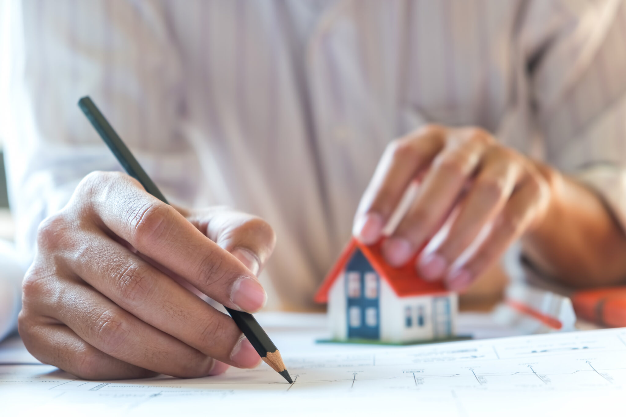 Pessoa a fazer contas à mão de quanto pode poupar a amortizar o crédito habitação