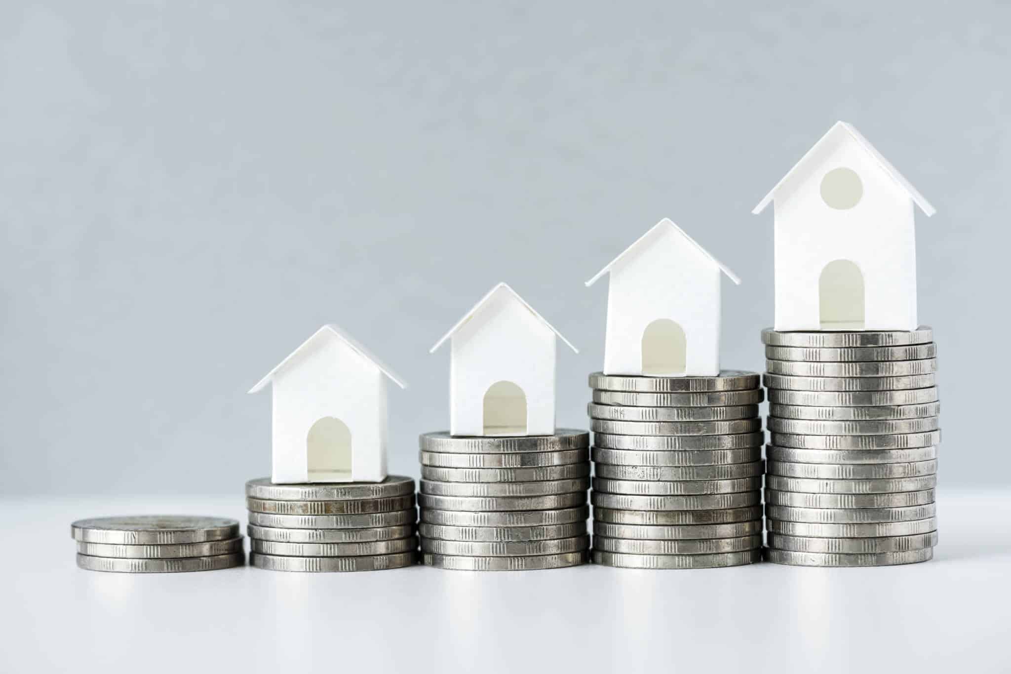 casas em miniatura em cima de pilhas de moedas, representando a subida dos juros