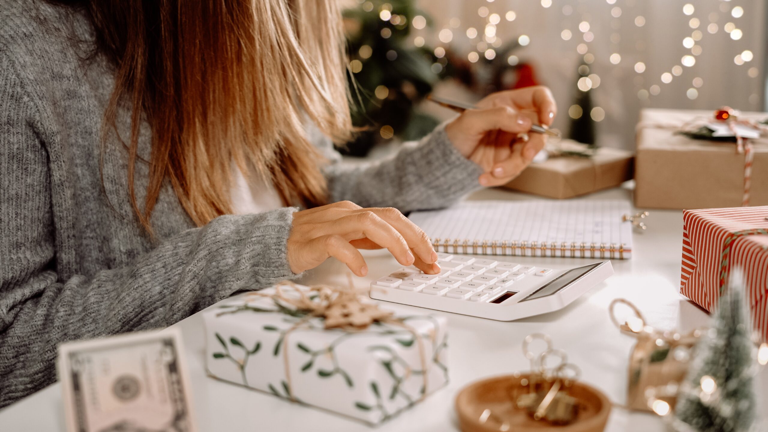 Mulher a utilizar calculadora e bloco para fazer lista de Natal