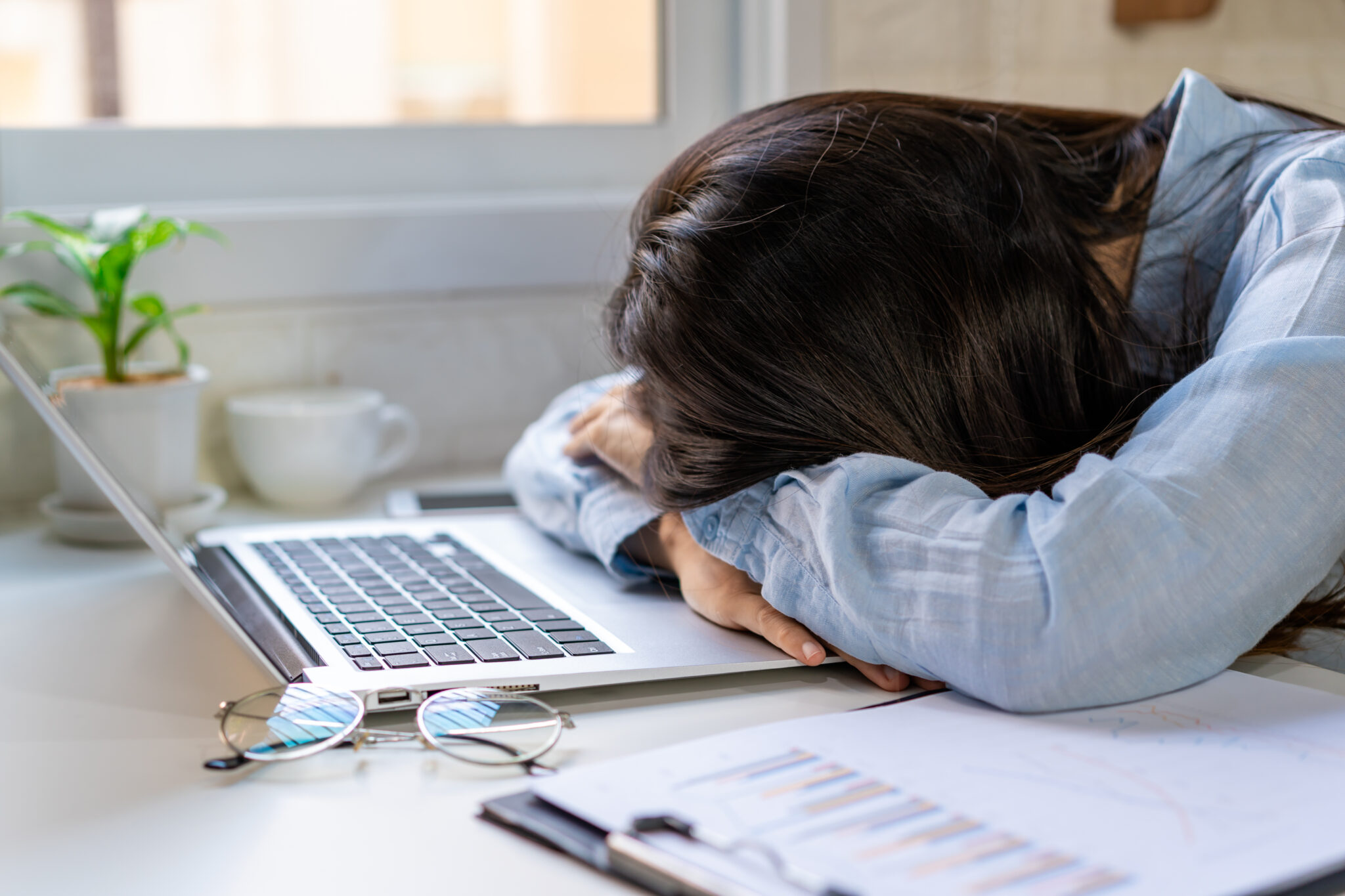 mulher com ansiedade financeira com a cabeça pousada no computador após analisar as suas contas