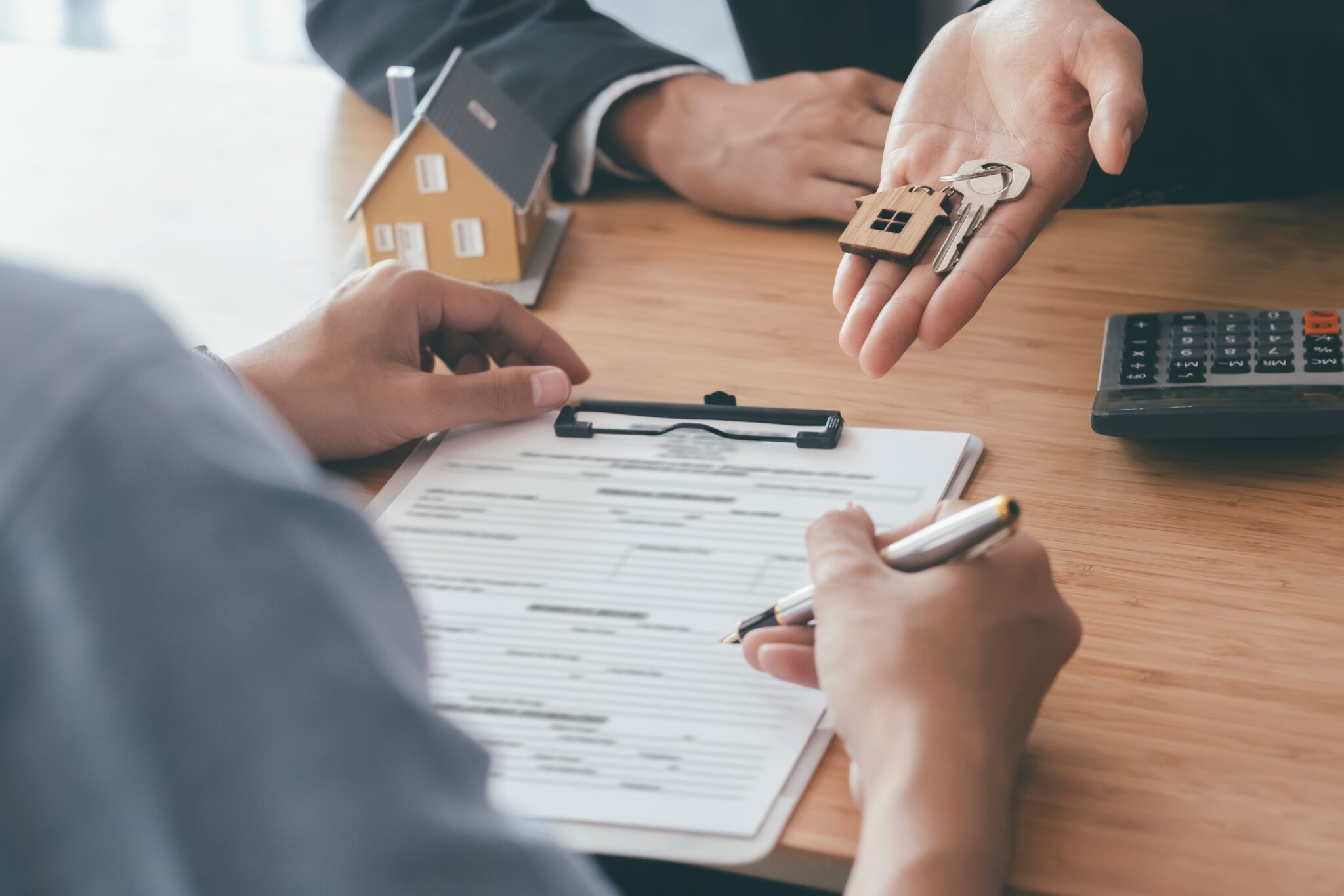 Cliente a assinar contrato a receber chave simbolizando arrendar ou comprar em 2023