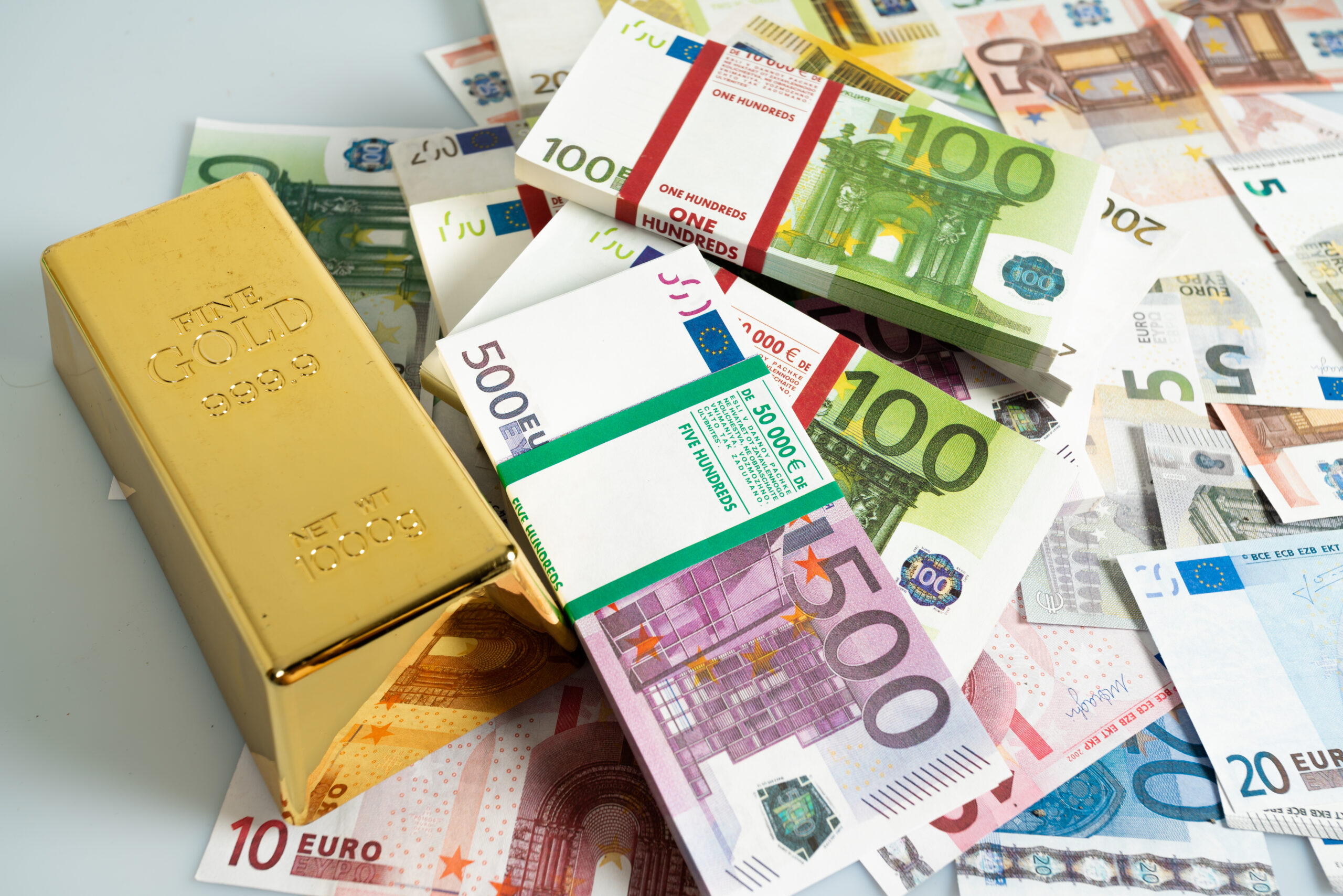 em cima de muitos moilhos de notas de euro, de fifeentes valores, vemos uma barra de ouro, devidamente marcada, remetendo para o processo da sua compra