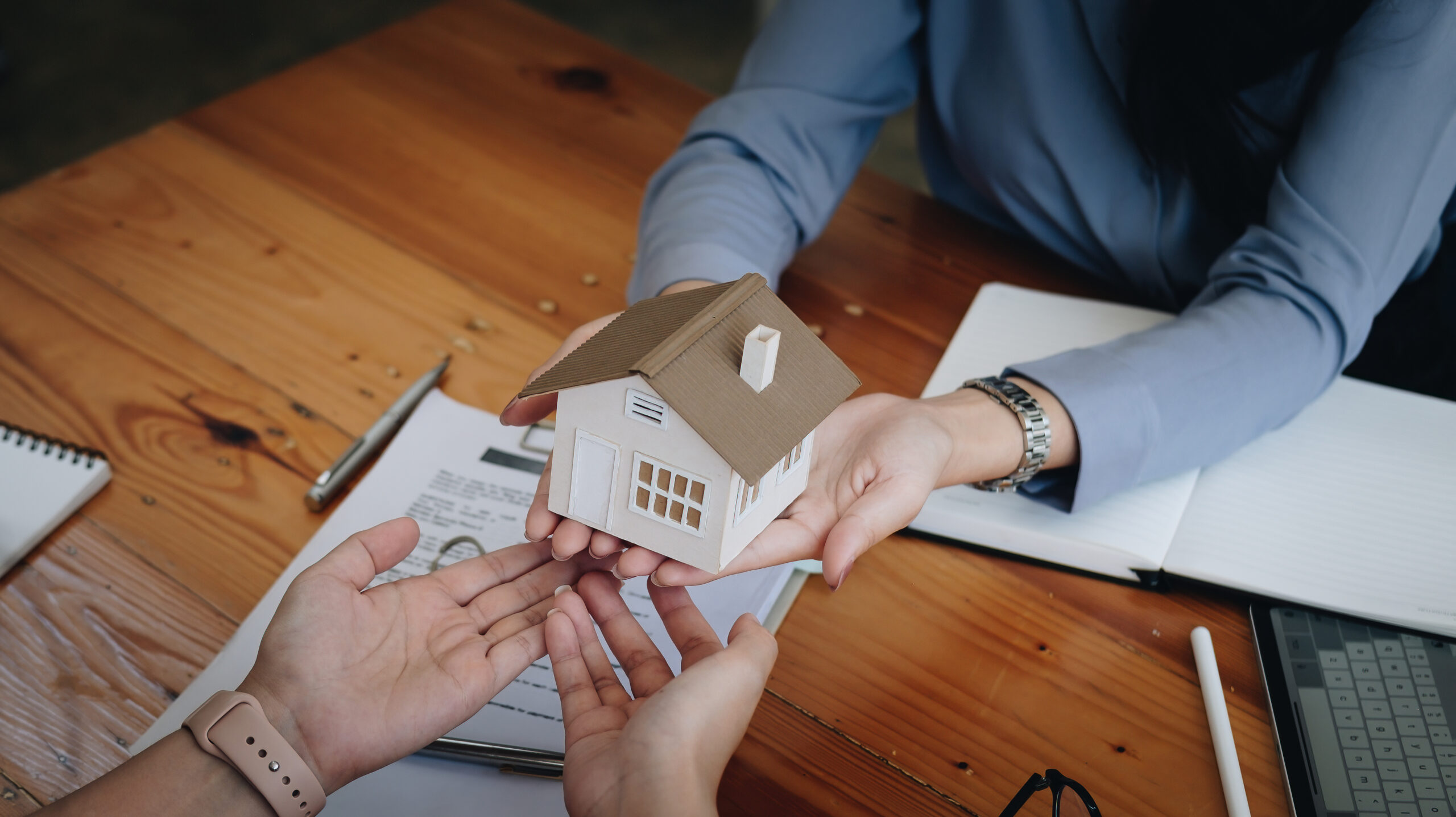 agente imobiliária a segurar miniatura de casa