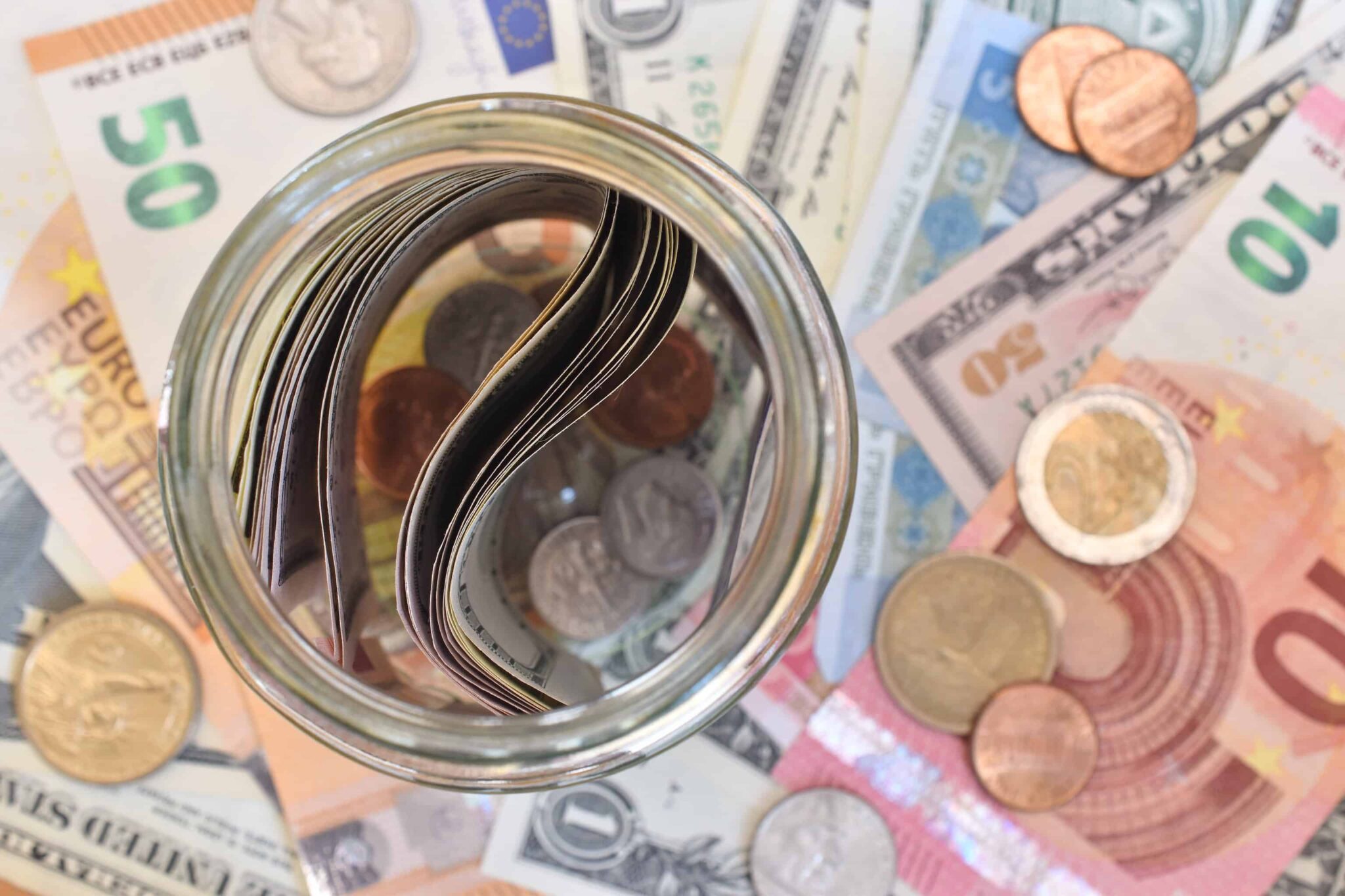 Frasco com notas dentro e notas e euros por baixo simbolizando deduções de IRS