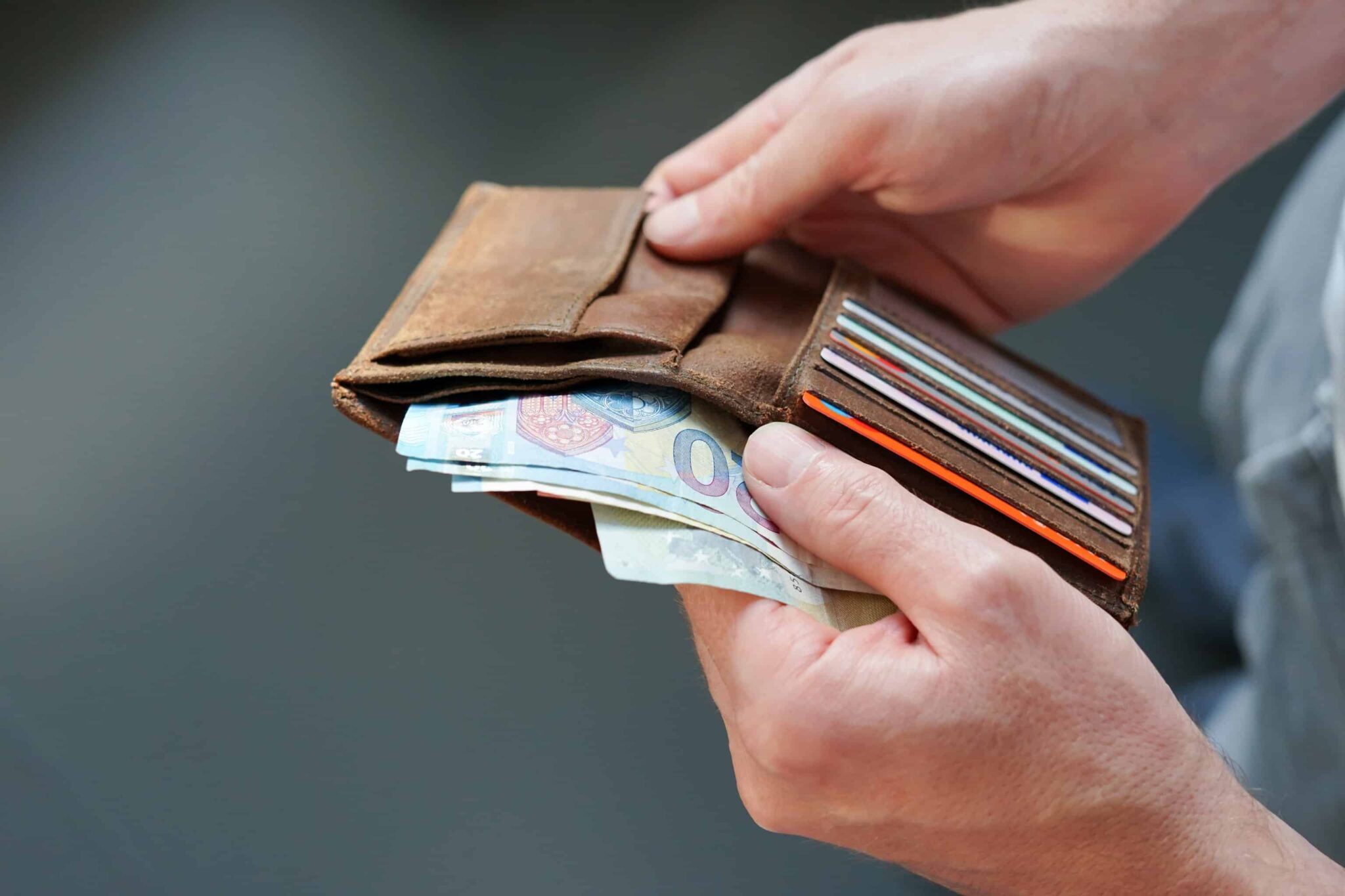 home abre carteira de bolso e conta as notas de euro que tem, ilustrando a importancia de reduzir gastos para poupar dinheiro mensalmente