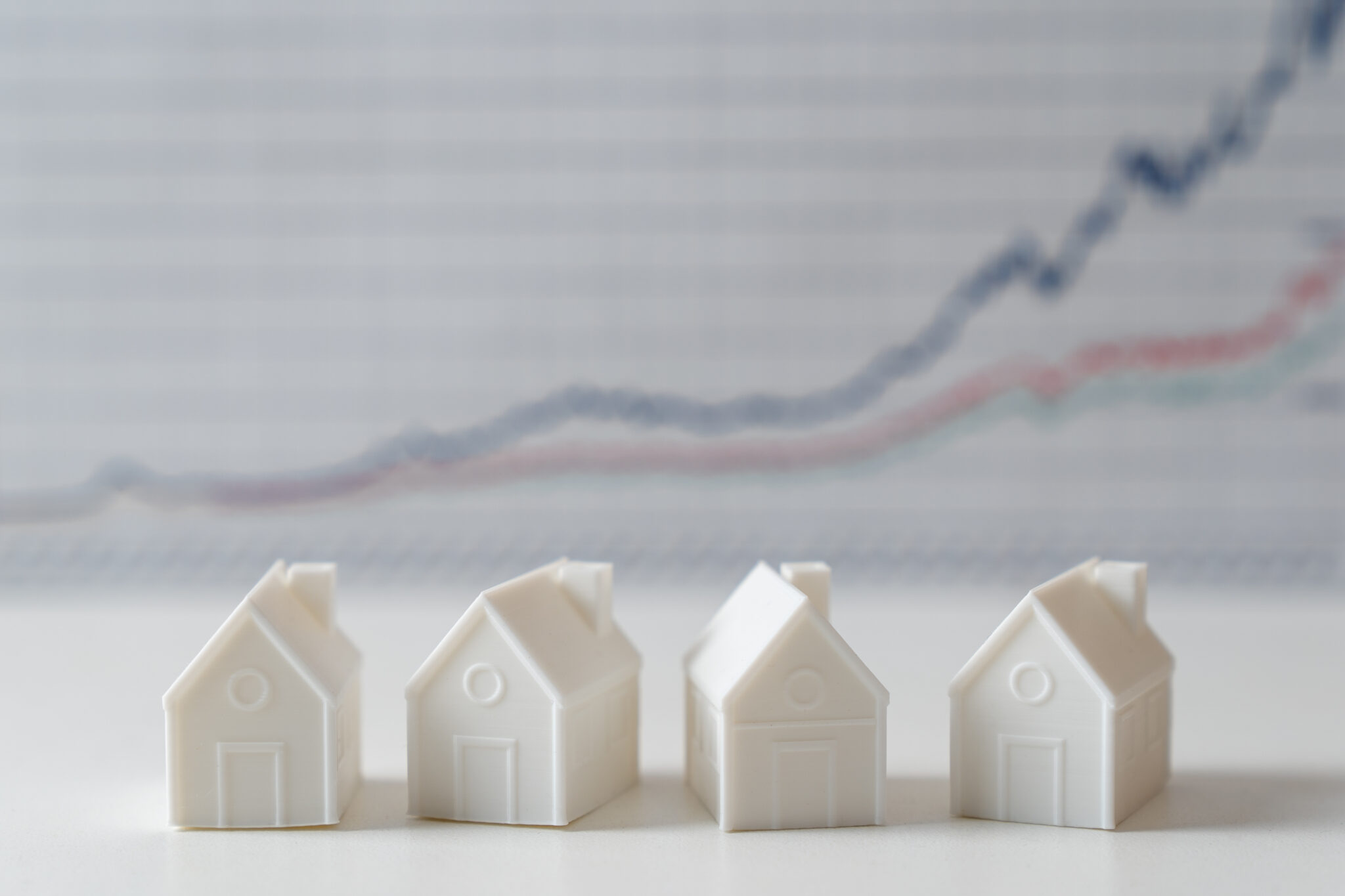 quatro casas brancas em miniatura e um gráfico de evolução a demonstrar que as prestações sobem em março novamente no crédito habitação