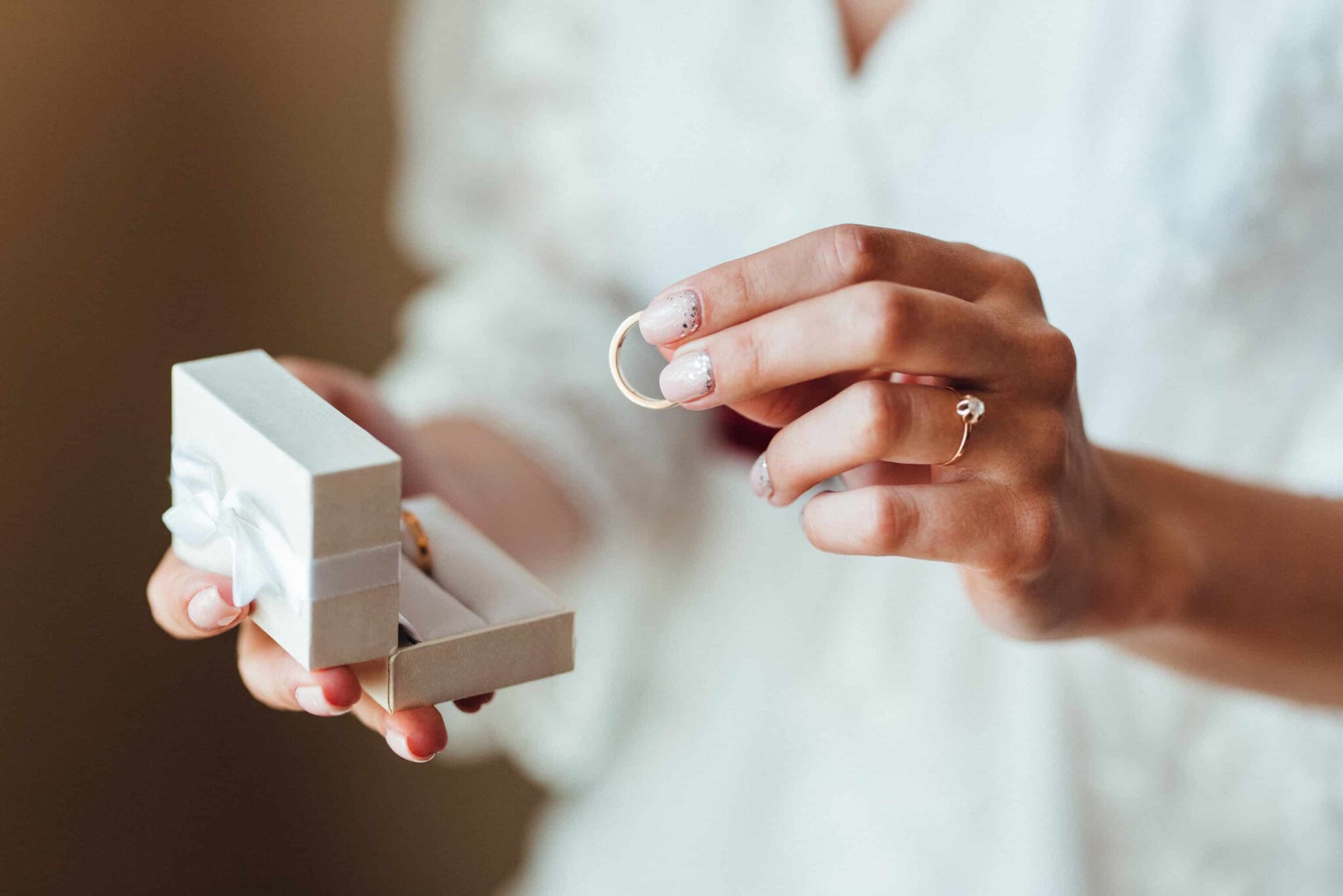 Mãos de mulher a segurar caixa de alianças e aliança de casamento civil