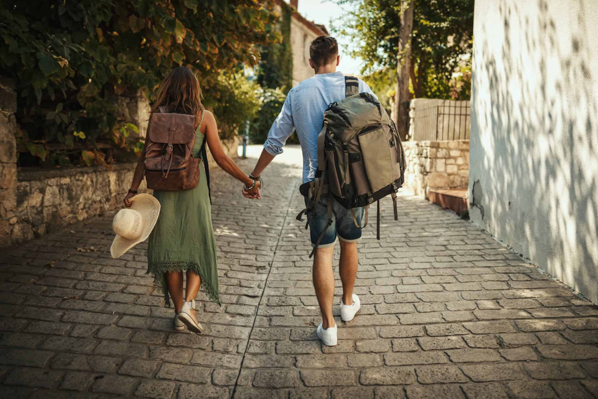 um casal de jovens turistas a caminhar pelas ruas antigas de uma cidade, a procurar um alojamento local