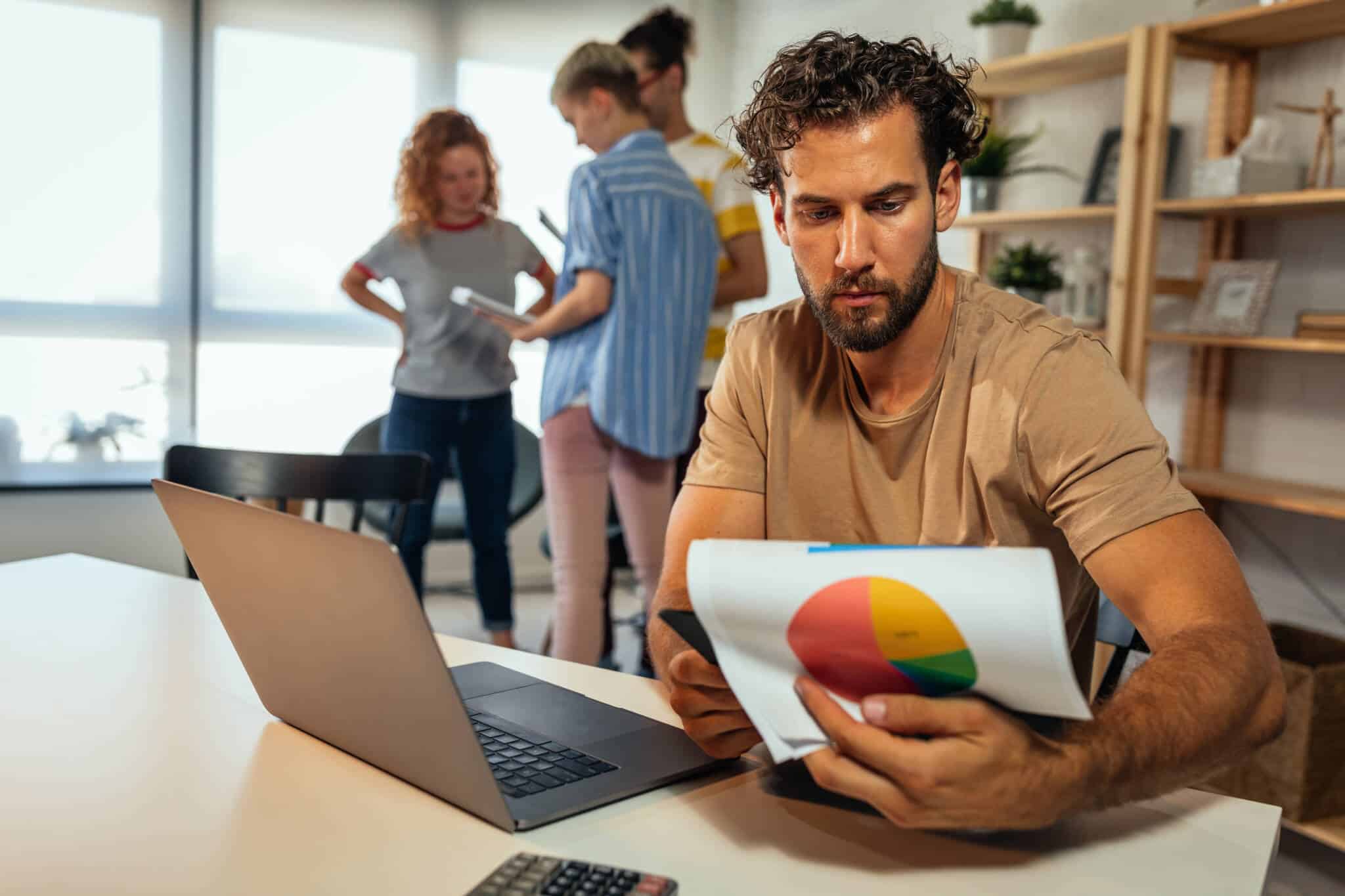 grupo de jovens em ambiente de trabalho estudam documentação, decidindo empreender em época de crise