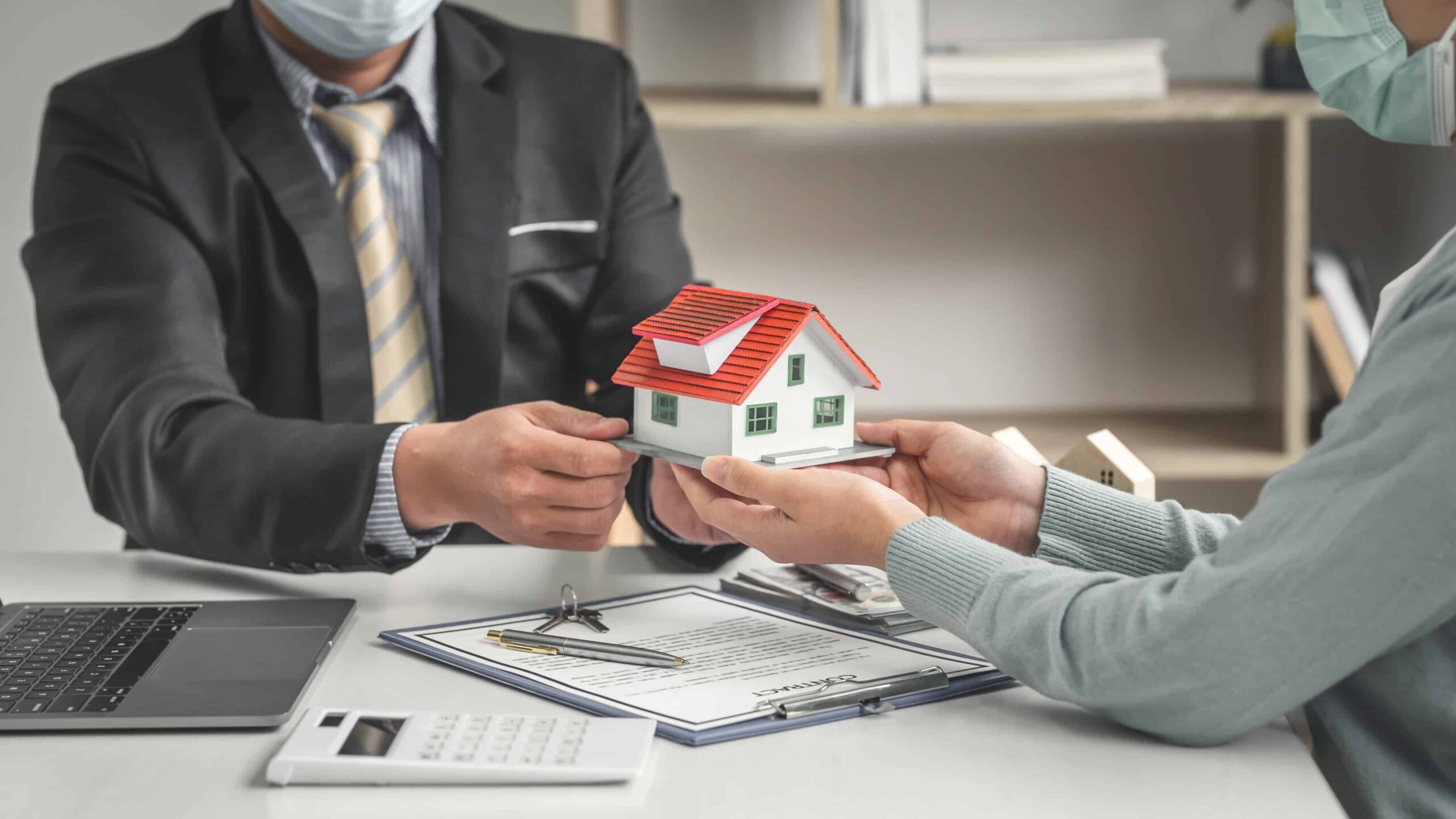 agente imobiliário a entregar casa em miniatura a cliente