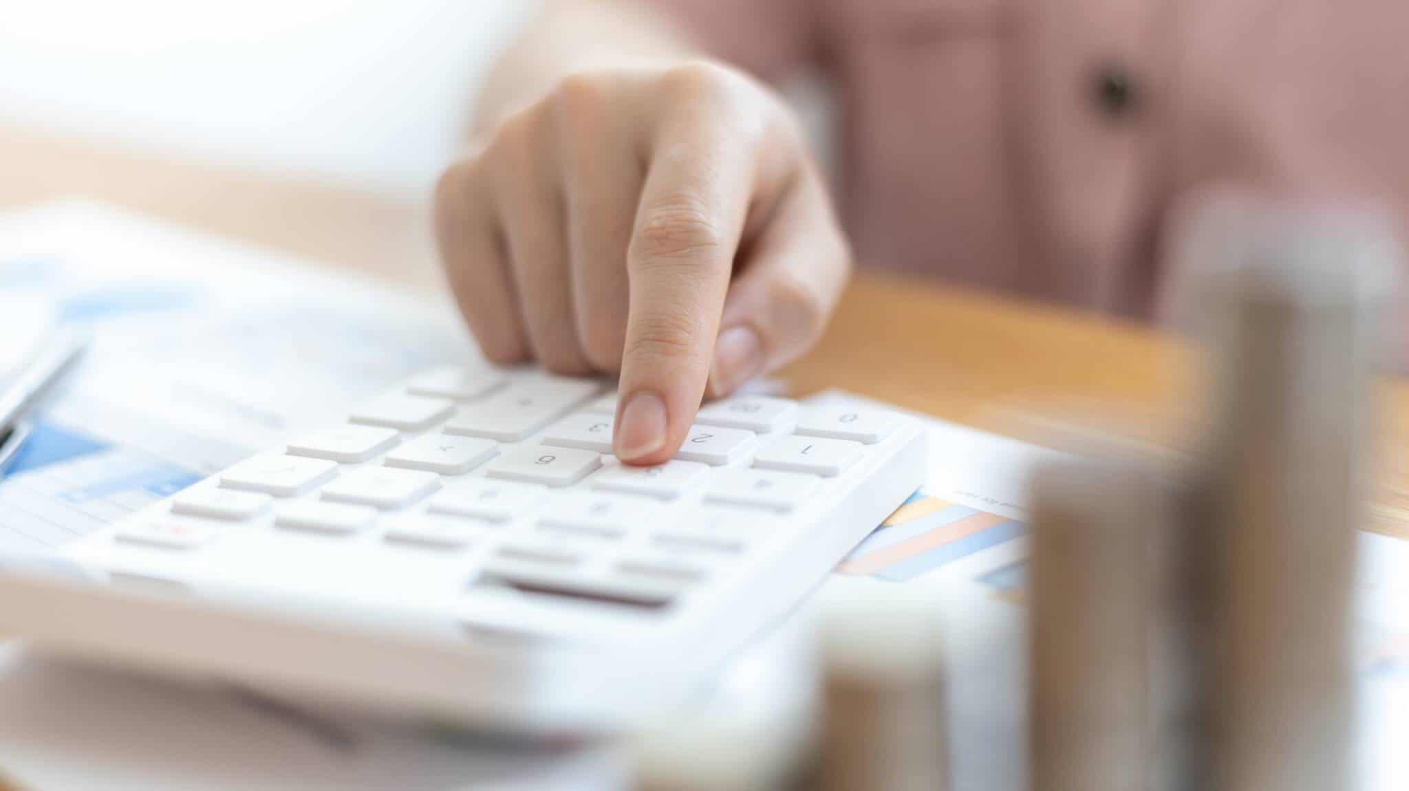 Mão a mexer em calculadora simbolizando contas sobre declaração de investimento mobiliário no IRS