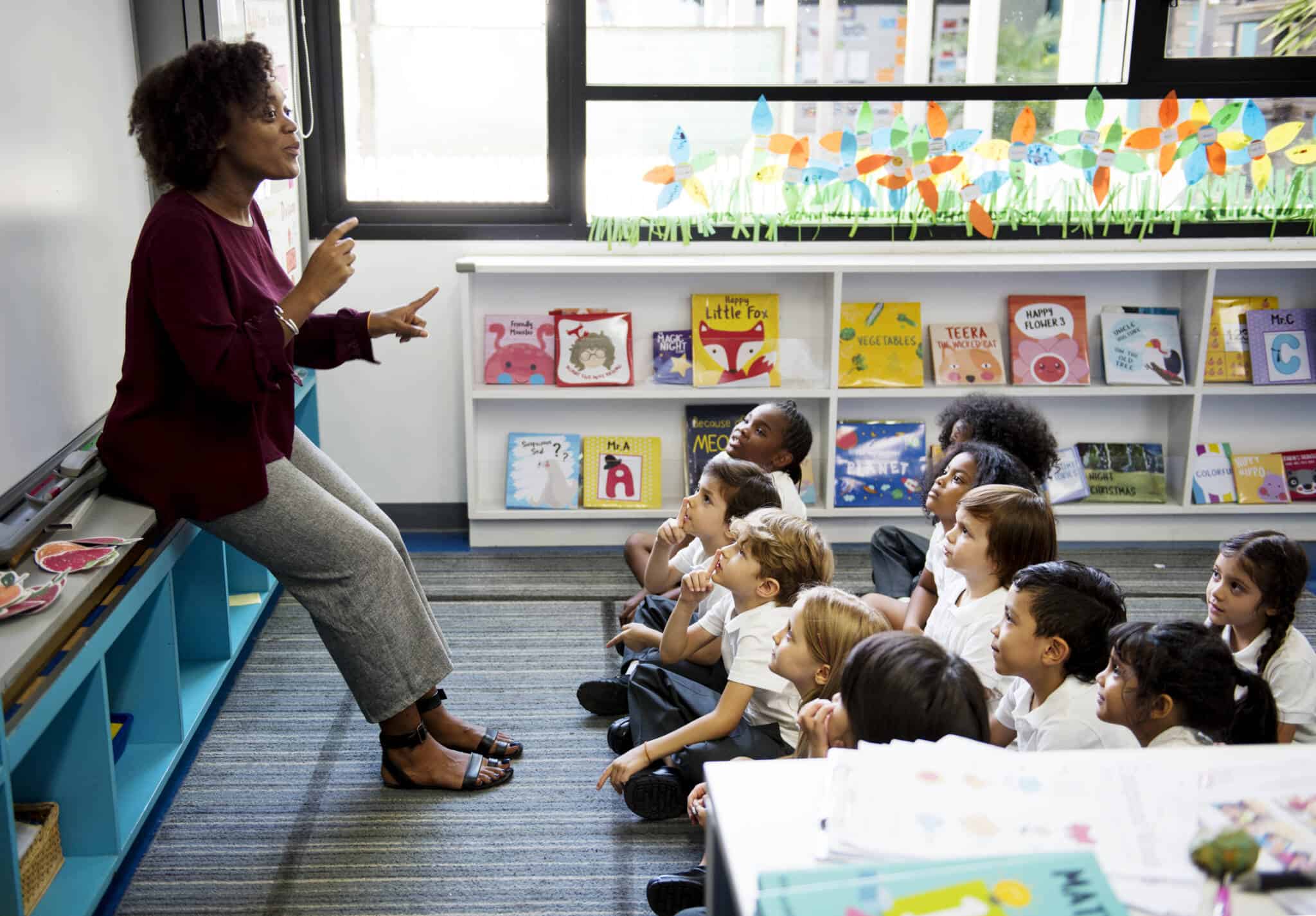 na sala de infantário um grupo de crianças escutam com atenção a professora especializada em necessidades educativas especiais
