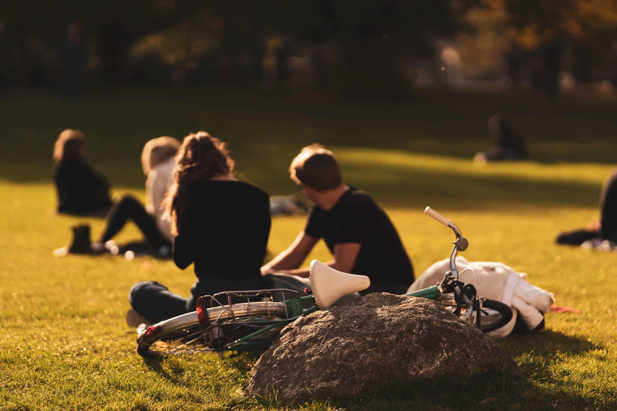 alguns jivens espalhados pelo relvado de um jardim público, junto das suas bicicletas, a aproveitar as diversas formas de ocupar o tempo livre