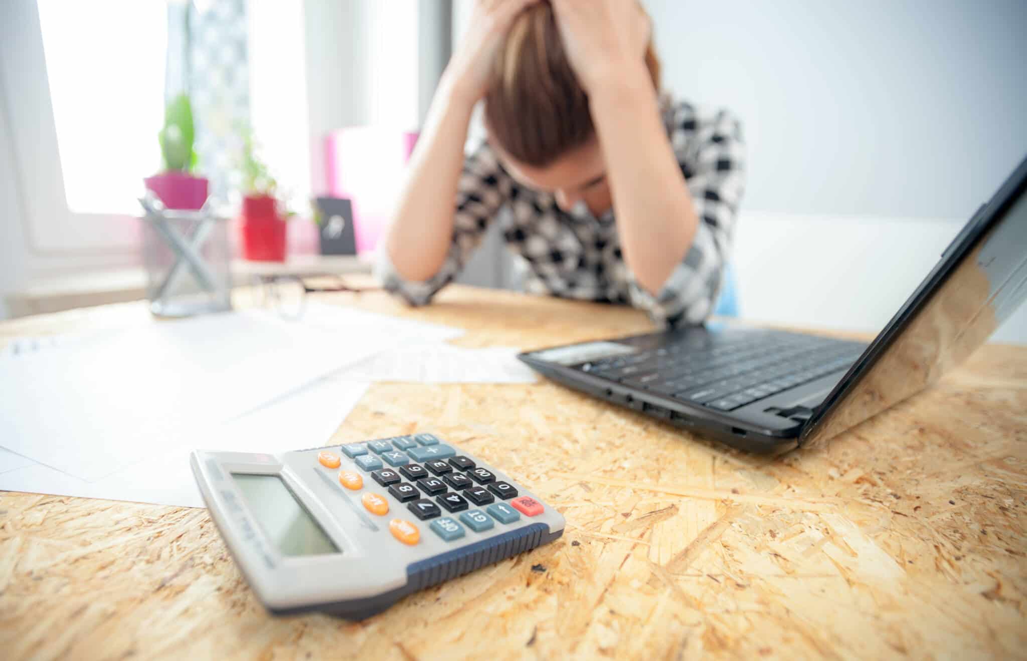 mulher de cabeça baixa a tentar evitar a ansiedade financeira após ver as suas despesas