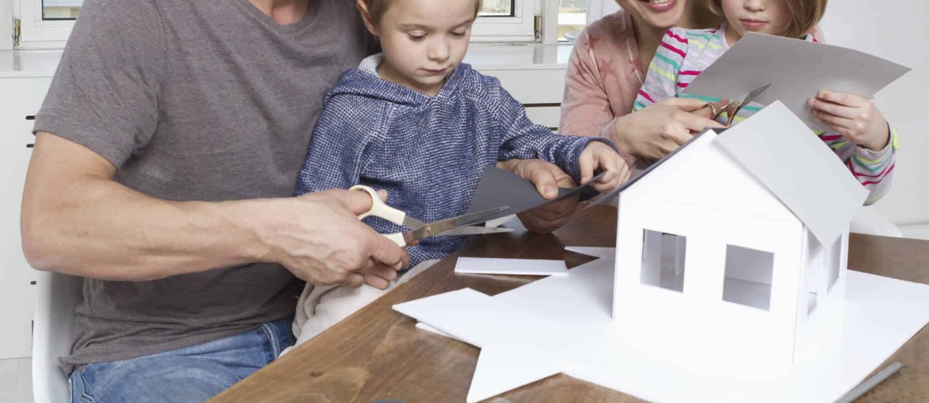 Família com maquete de casa representando mais-valias da venda de casa construída