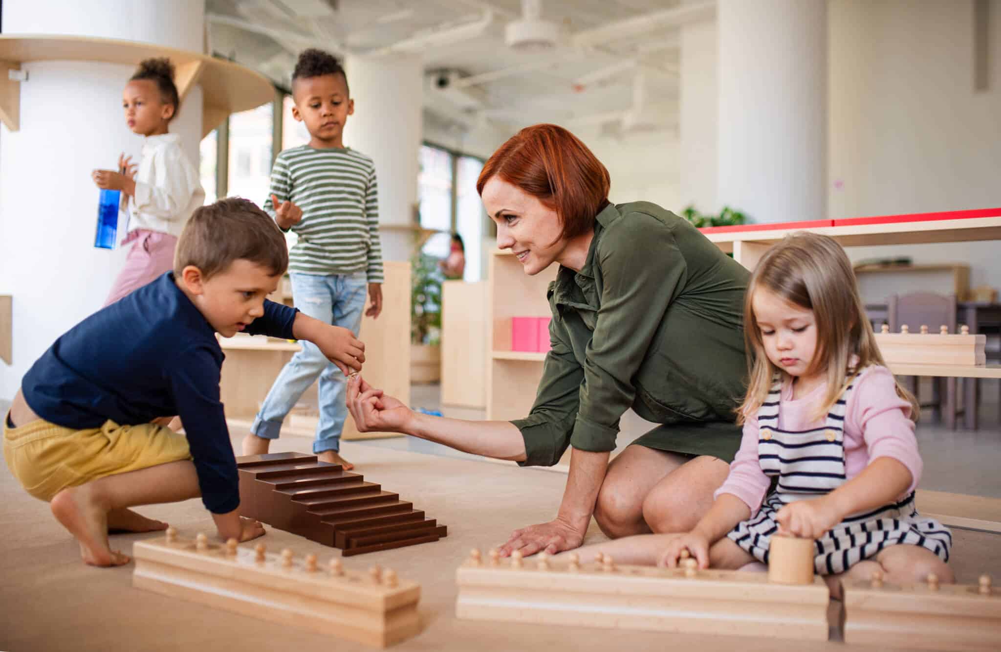 grupo misto de crianças, de diferentes nacionalidades, partilhma jogos de educação Montessori,uma sala de infantário, orientados pela educadora