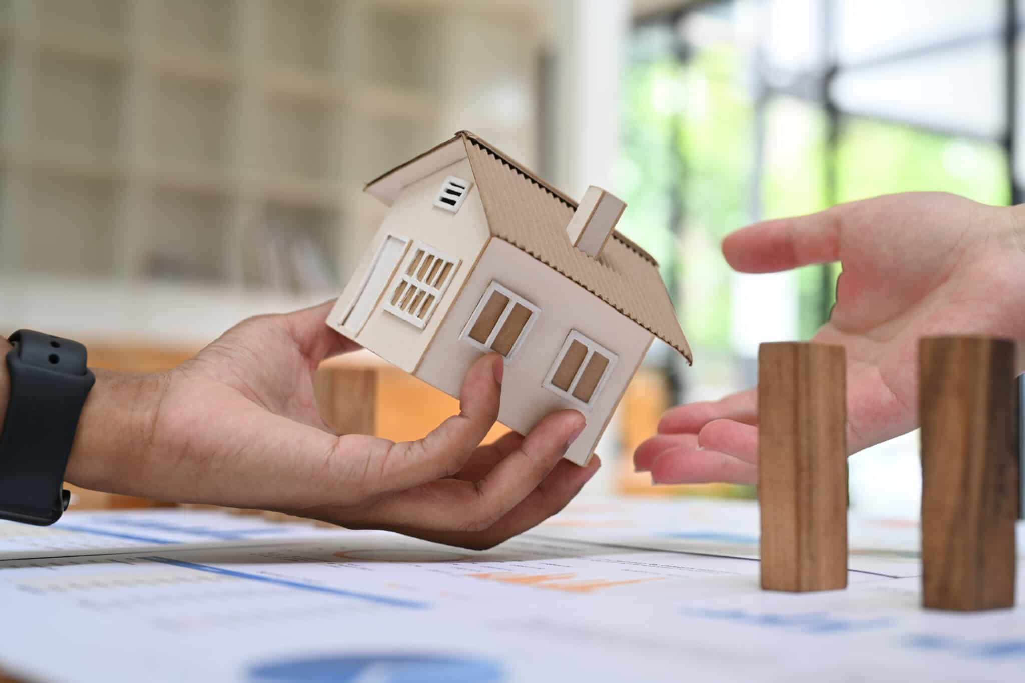 uma mão a segurar uma casa e outra estendida a ilustrar que não podem ser mudadas as condições de uma proposta de crédito habitação após um contrato ser assinado