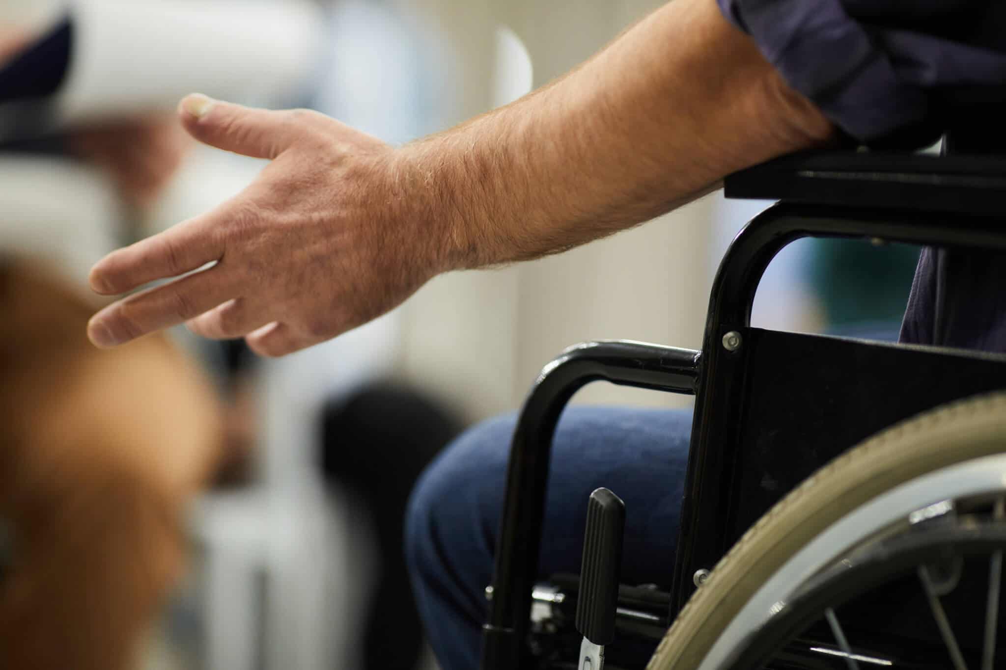 homem em cadeira de rodas estende a mão como forma de desagrado por não ser respeitado o atendimento prioritário