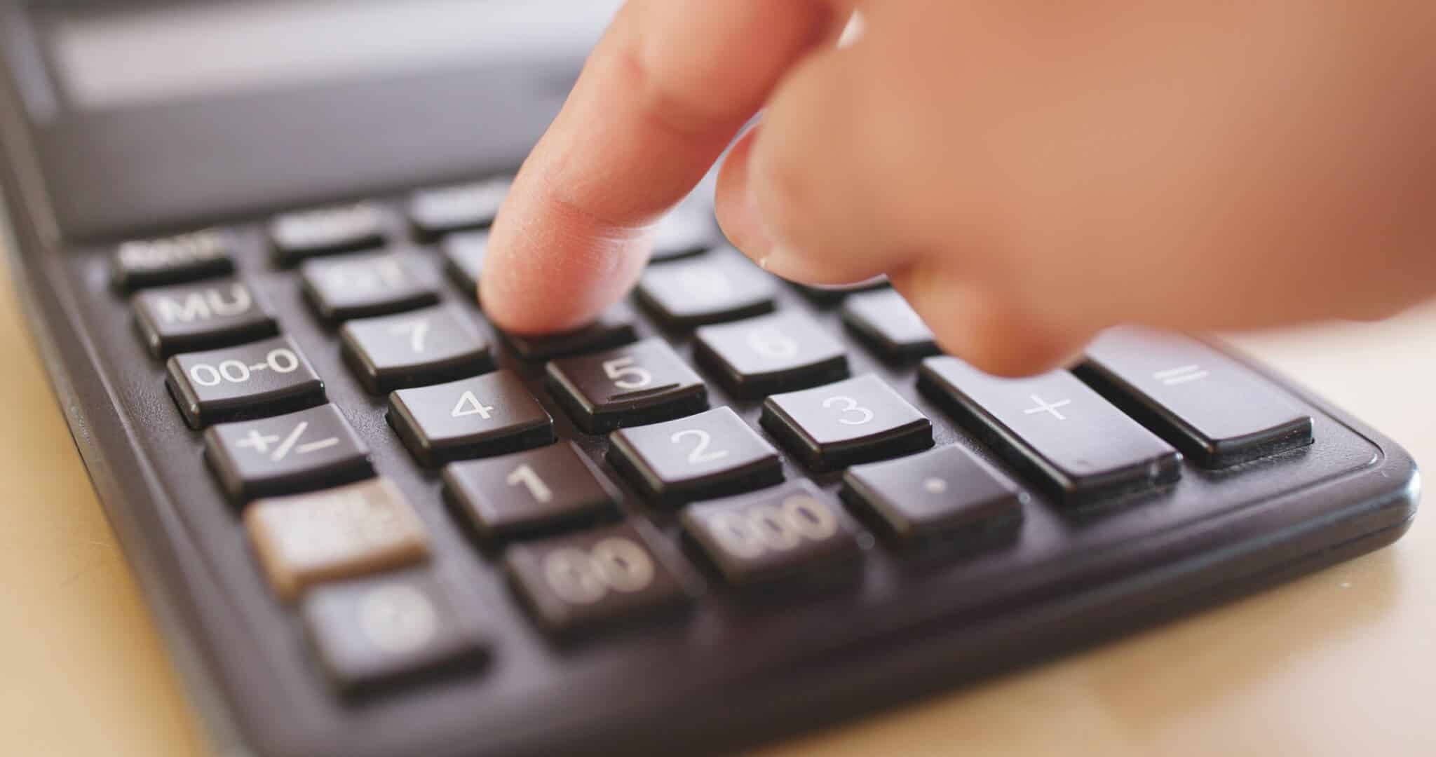 alguém a usar uma calculadora numa alusão às mudanças nos rendimentos no segundo semestre de 2023 - novas tabelas de retenção na fonte de IRS