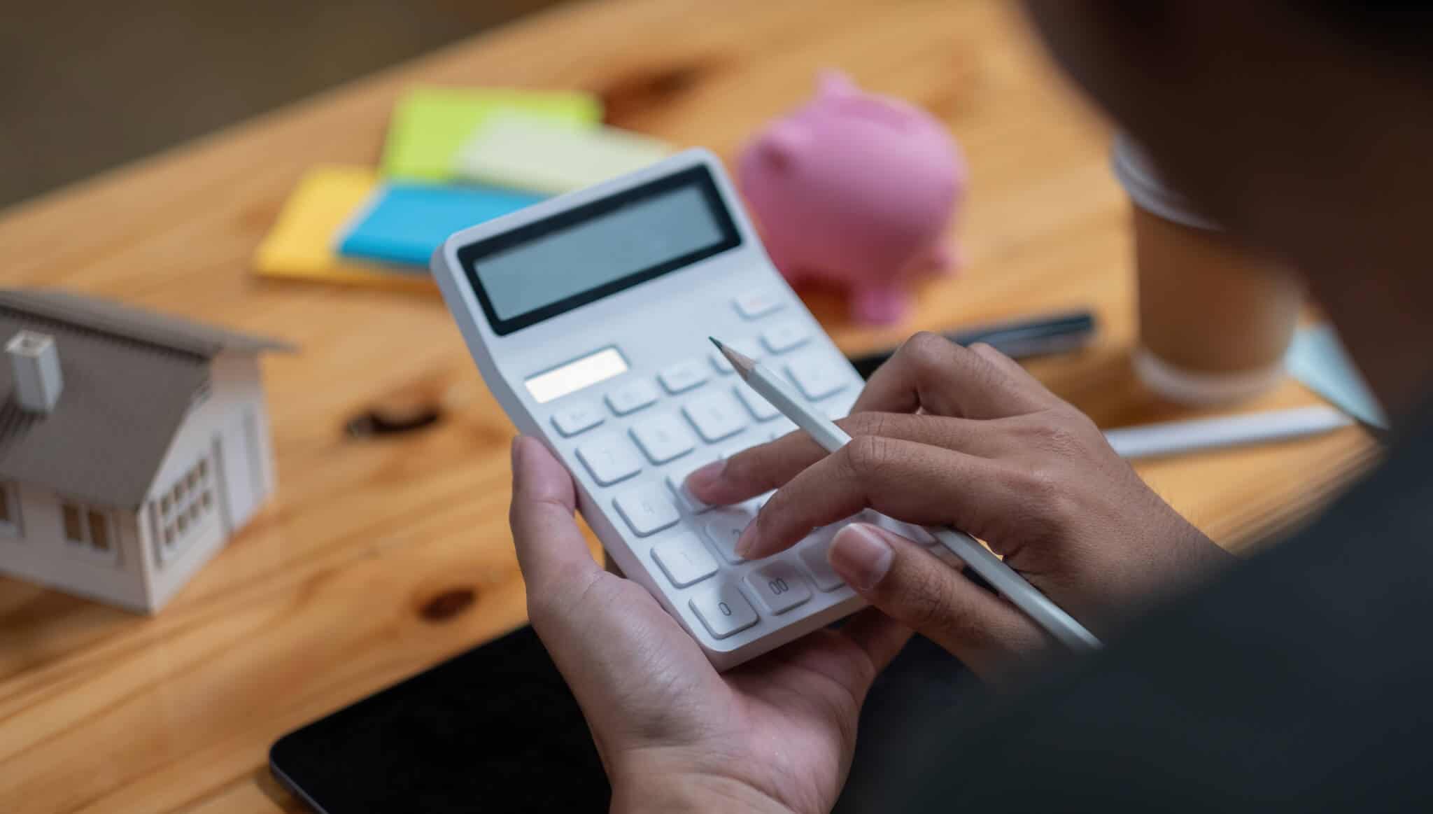 pessoa a fazer contas numa calculadora para ter a resposta de quanto dinheiro preciso para comprar casa