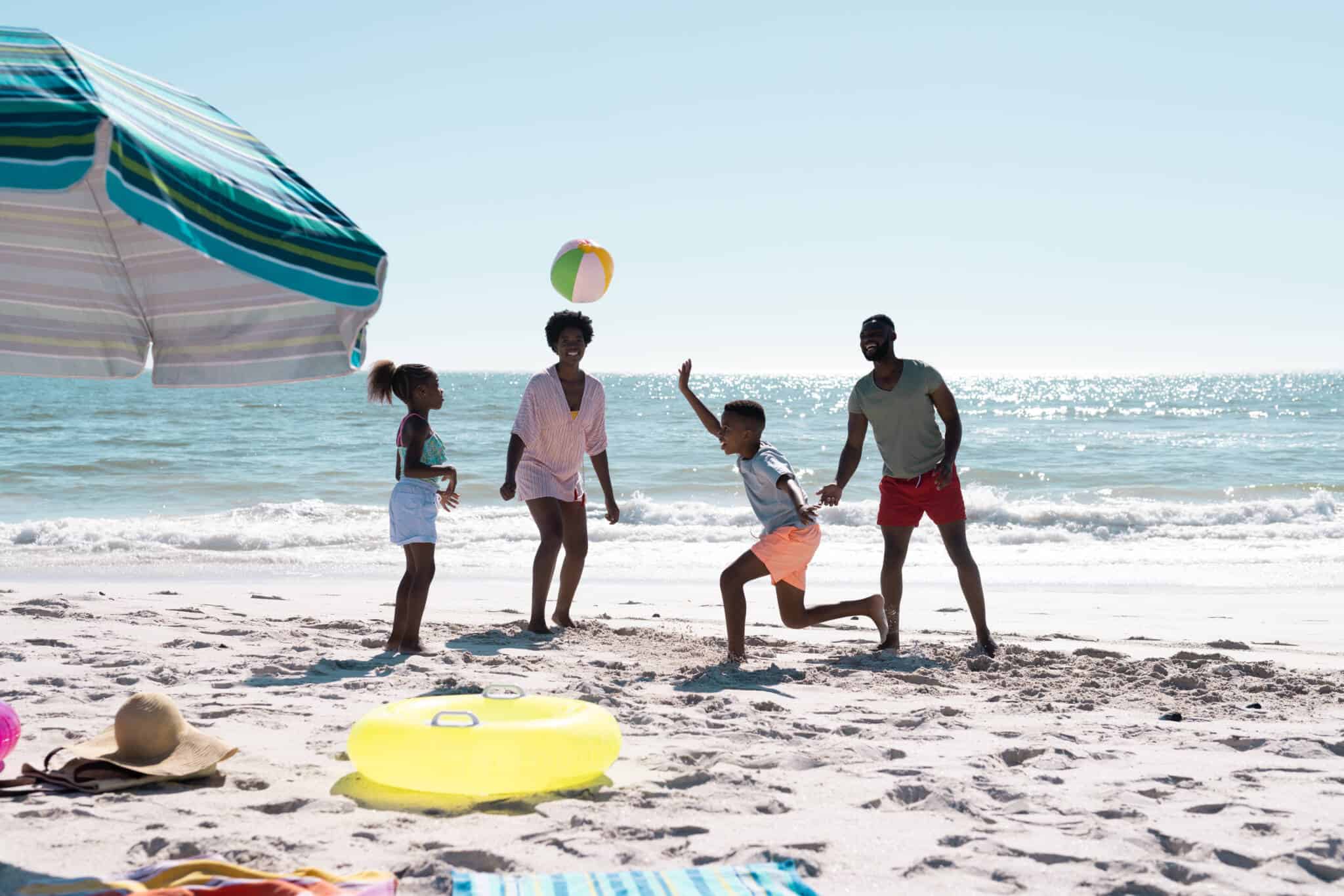 familia com duas crianças, na praia, a fazer atividades com filhos em tempo de férias