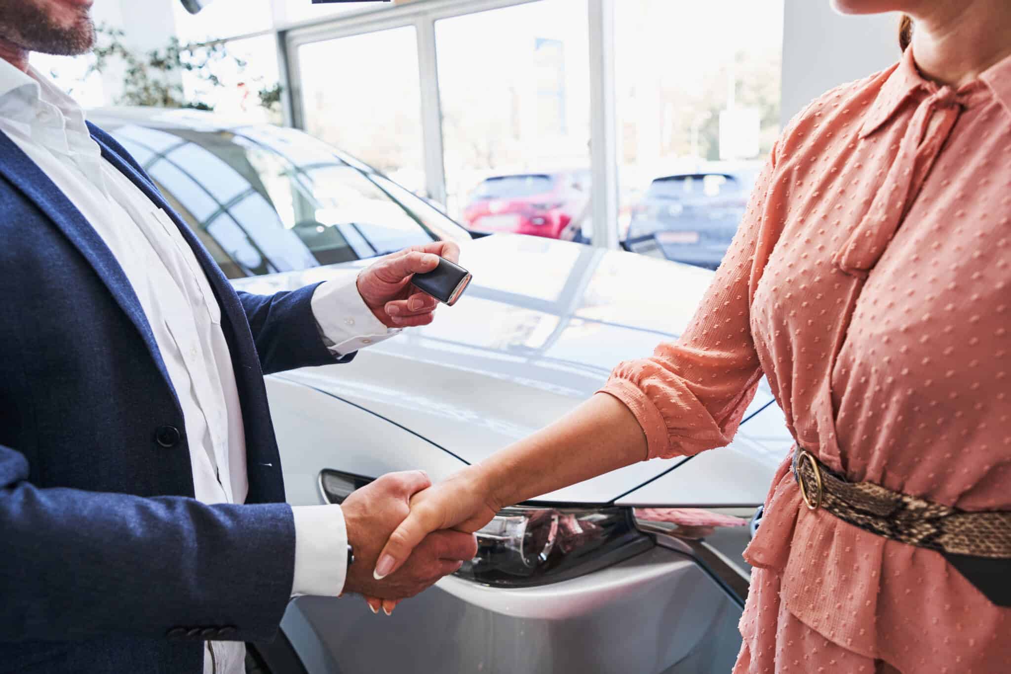 home e mulher, em abiente de stand automóvel, em momento de entrega de chave no seguimento de compra com crédito automóvel ou crédito pessoal