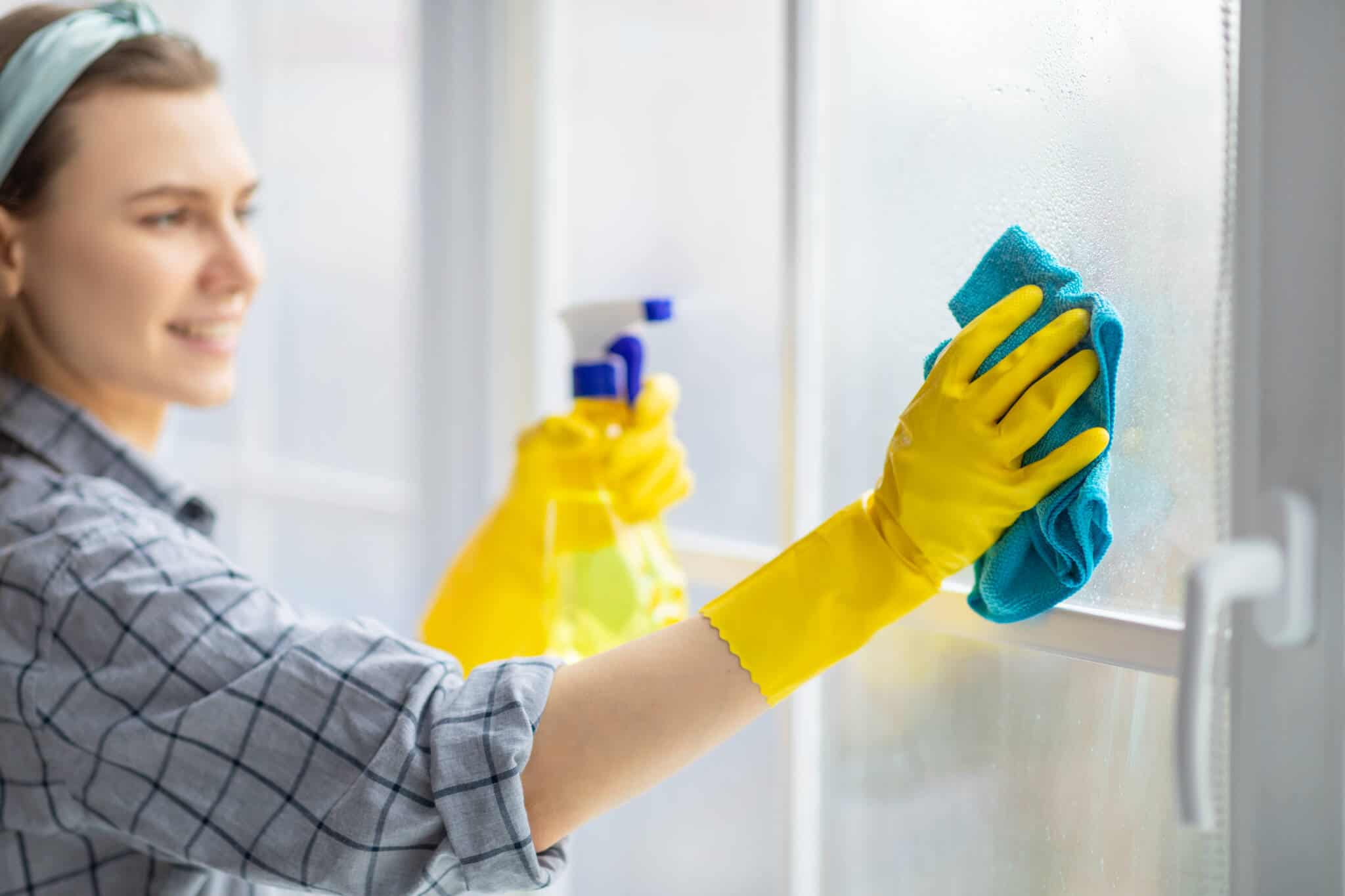 empregada doméstica a limpar os vidros de uma casa