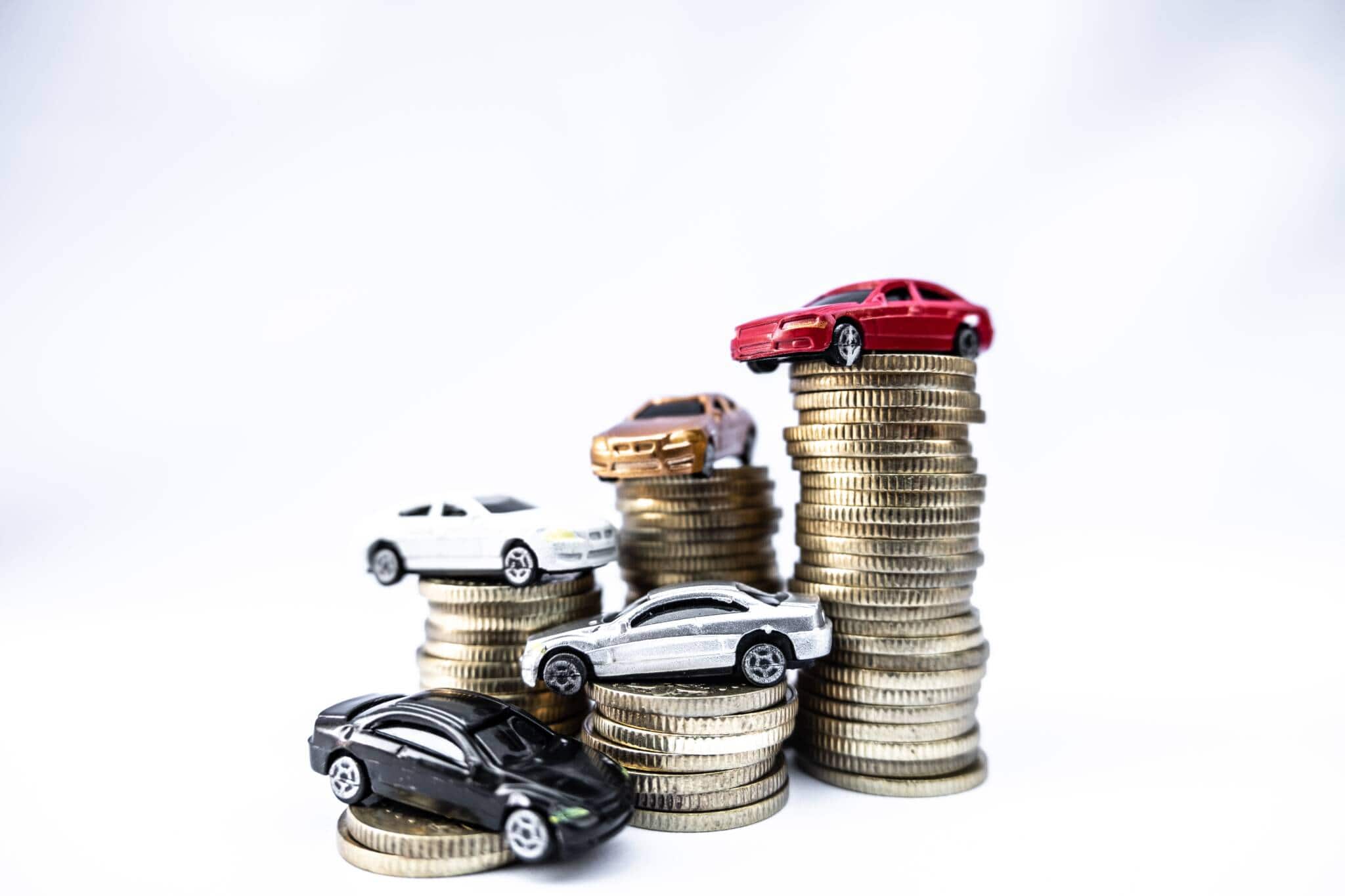várias pilhas de moedas com diferentes carros de brincar no seu topo ilustram o pagamento do IUC