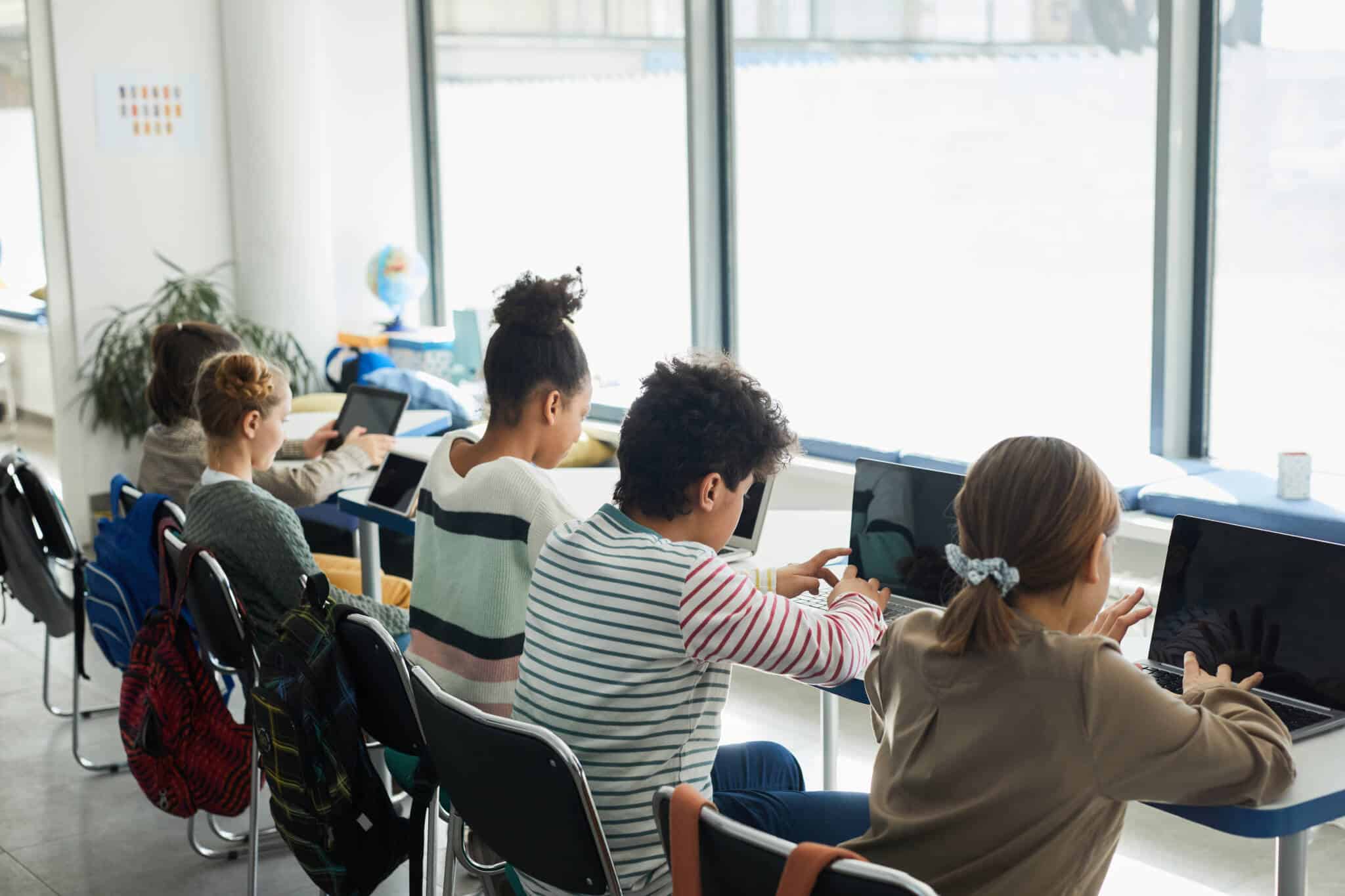 fila de crianças a estudar ao computador, numa sala de aulas preparada, no decorrer do Plano 23/24 Escola+