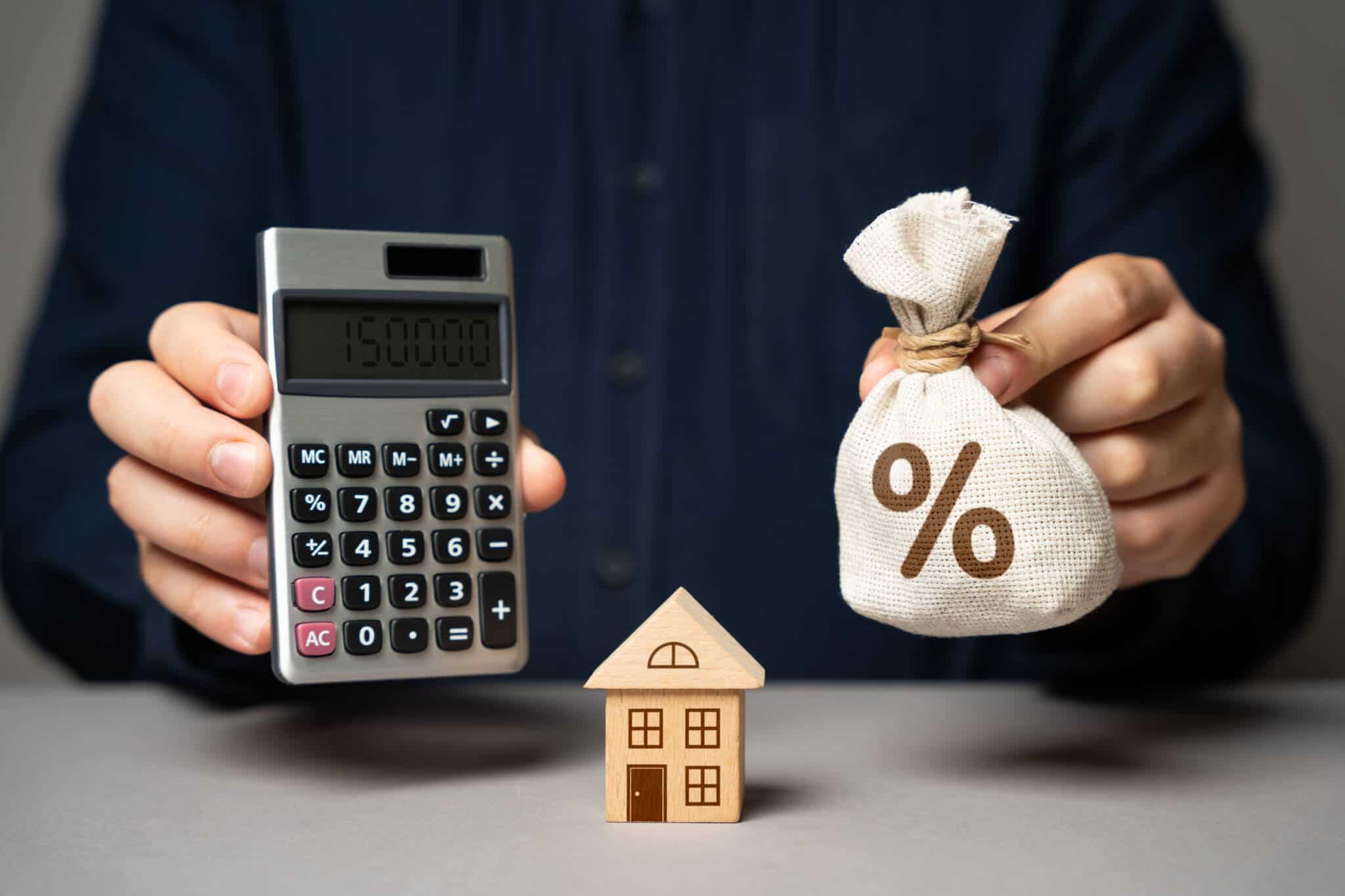 Pessoa com uma calculadora e uma casa a ilustrar a análise do MTIC e a TAEG na escolha de uma proposta de crédito