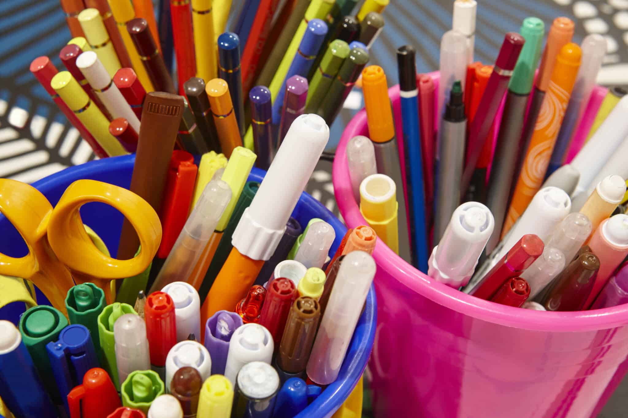Copos com canetas e lápis coloridos