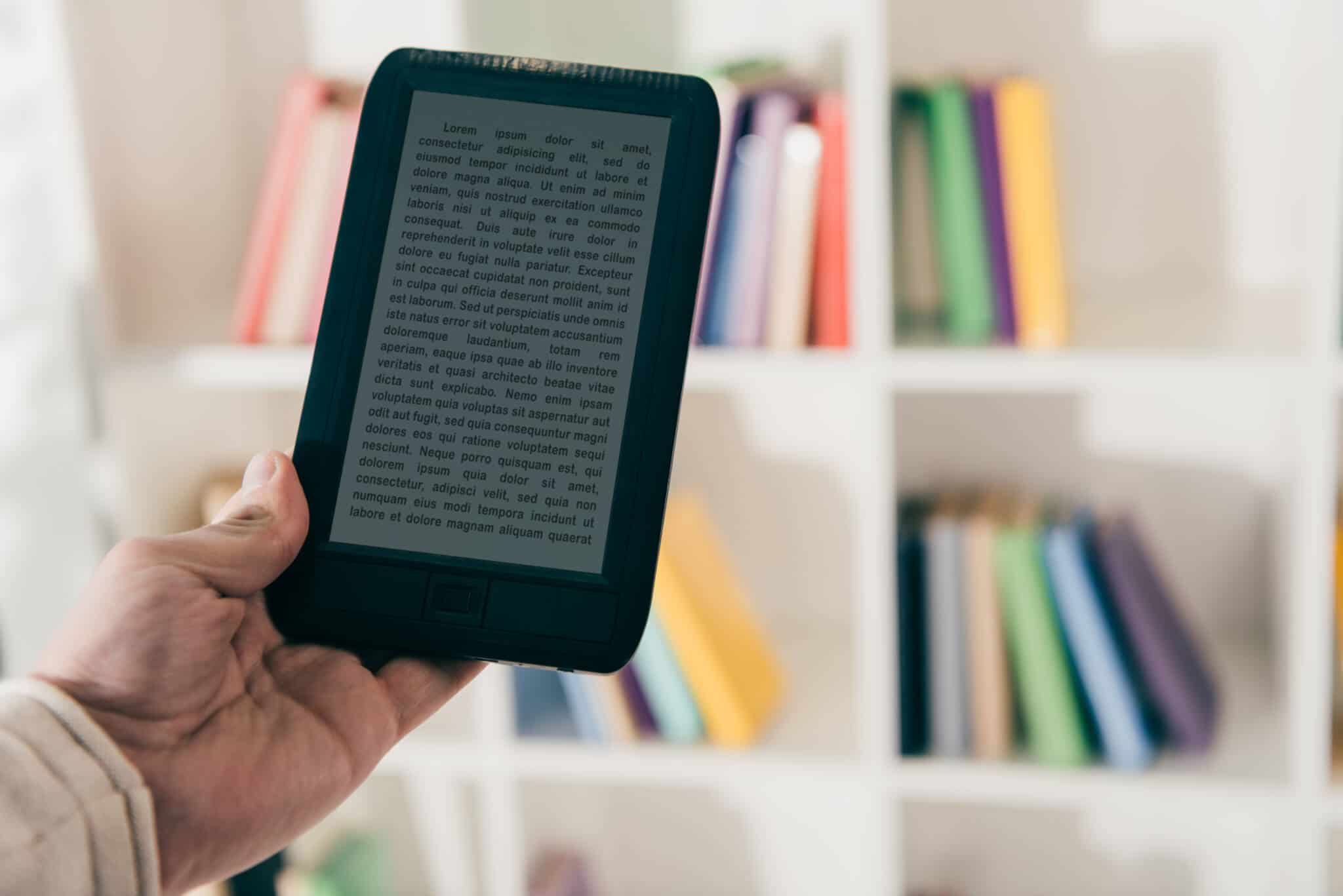 mão segira e-book em fundo desfocado de estante de livros, que alimentam paixão pela leitura