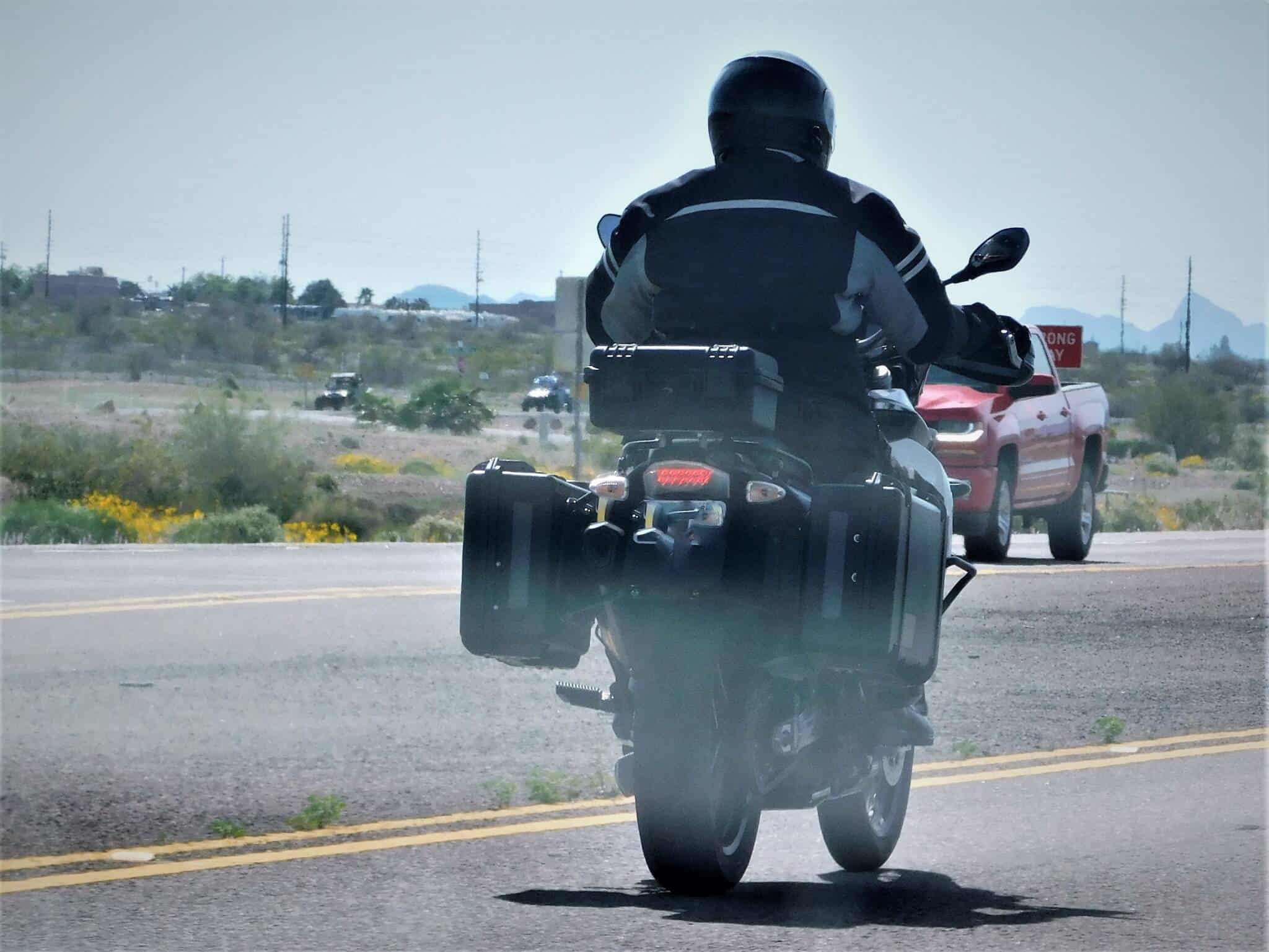 jovem rapaz de moto , com seguro para motociclos, a andar na estrada de asfalto