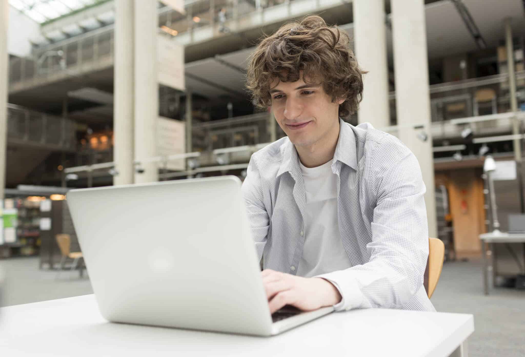 jovem a fazer os trabalhos escolares após escolher um computador novo