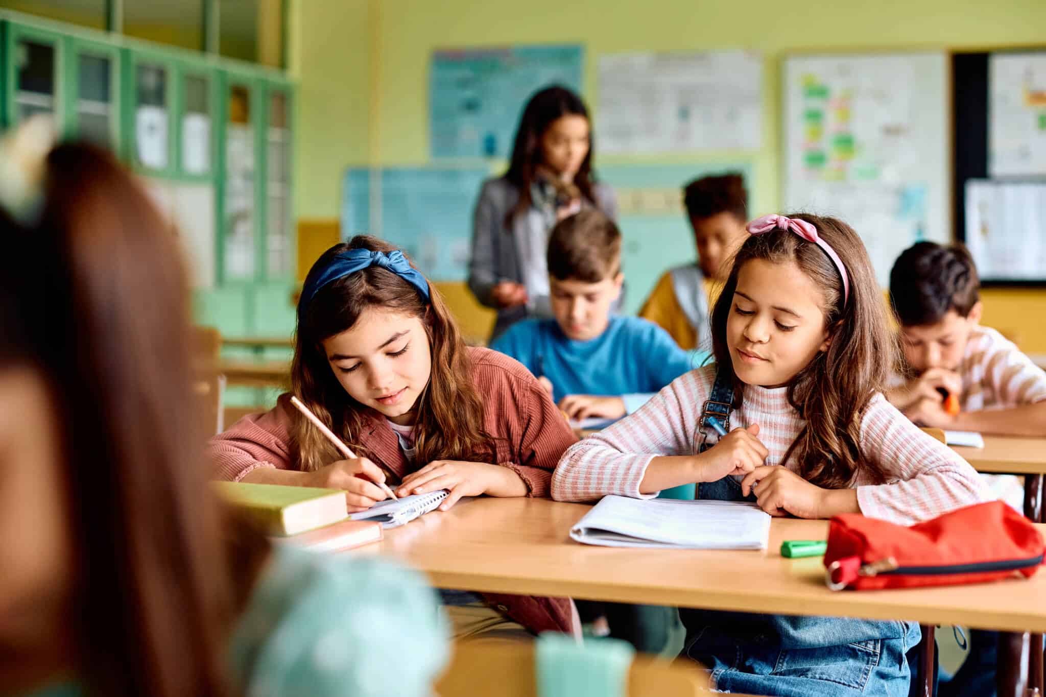 grupos de crianças, que recebem ação social escolar, na saula de aulas a fazer exercícios com o material assegurado por este apoio