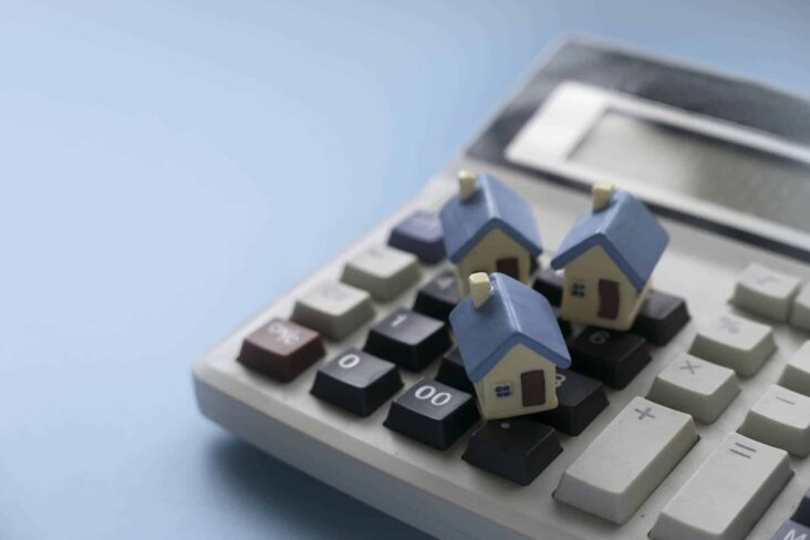 imagem de uma calculadora com várias casas em miniatura em cima numa alusão à renegociação e transferência de crédito habitação