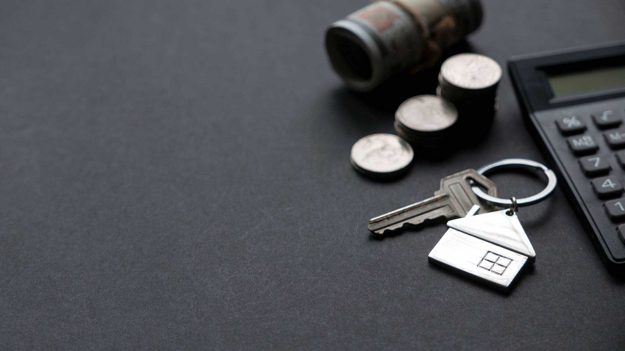 porta-chave com formato de uma casa. Ao seu lado uma pilha de moedas de euro