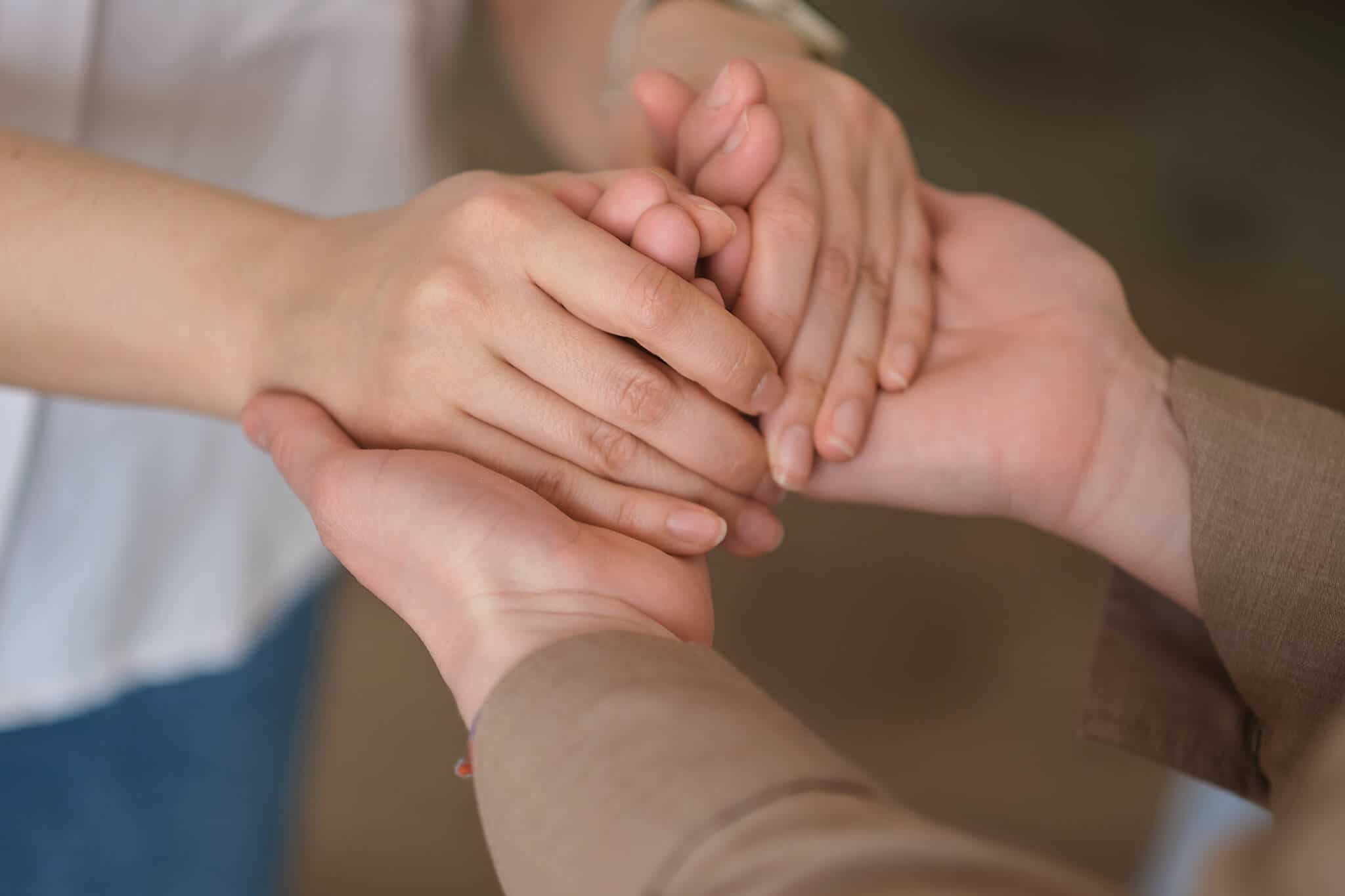 mãos de uma mulher mais velha seguram e acarinham mãos de jovem, representando o apoio que as pessoas com a saúde mental afetada precisam
