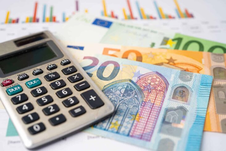 os termos financeiros BIC SWIFT e IBAN ilustradios por uma produção fotográfiica que mostra um molho de notas Euro, de diferentes valores e cores, junto a uma calculadora e documentos com gráficos