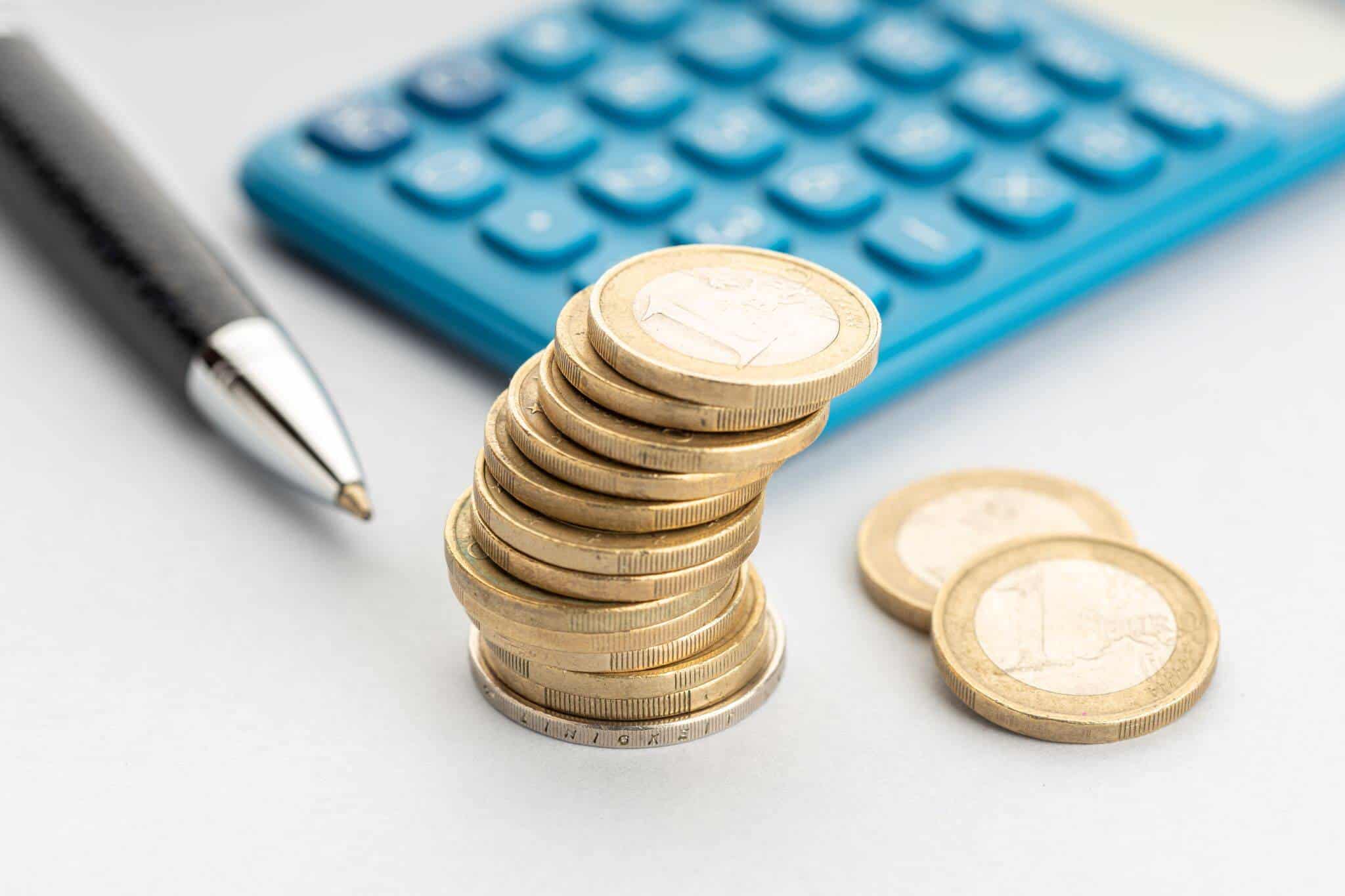 caneta, moedas de euro e calculadora azul