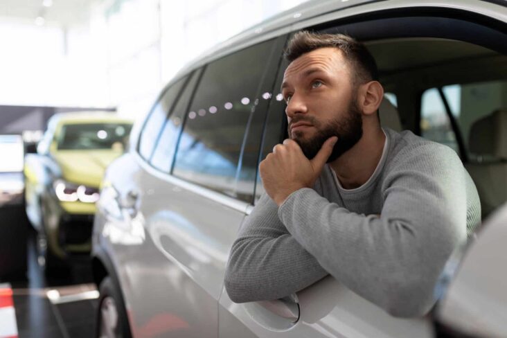 Homem indeciso se compra carro com crédito pessoal ou crédito automóvel