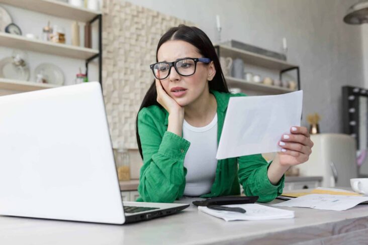 Mulher a olhar para o computador com dúvidas sobre a sua declaração de IRS aguarda validação