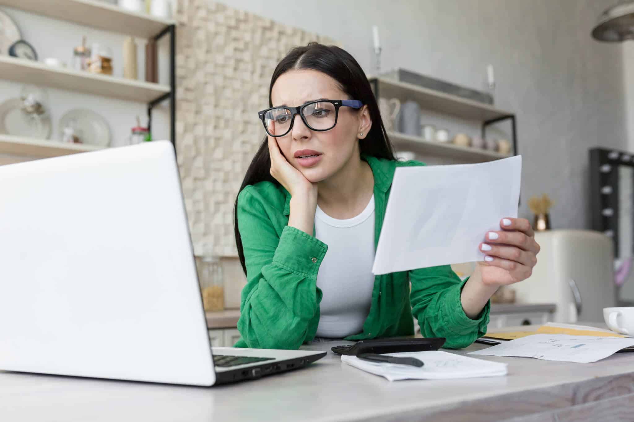 Mulher a olhar para o computador com dúvidas sobre a sua declaração de IRS aguarda validação