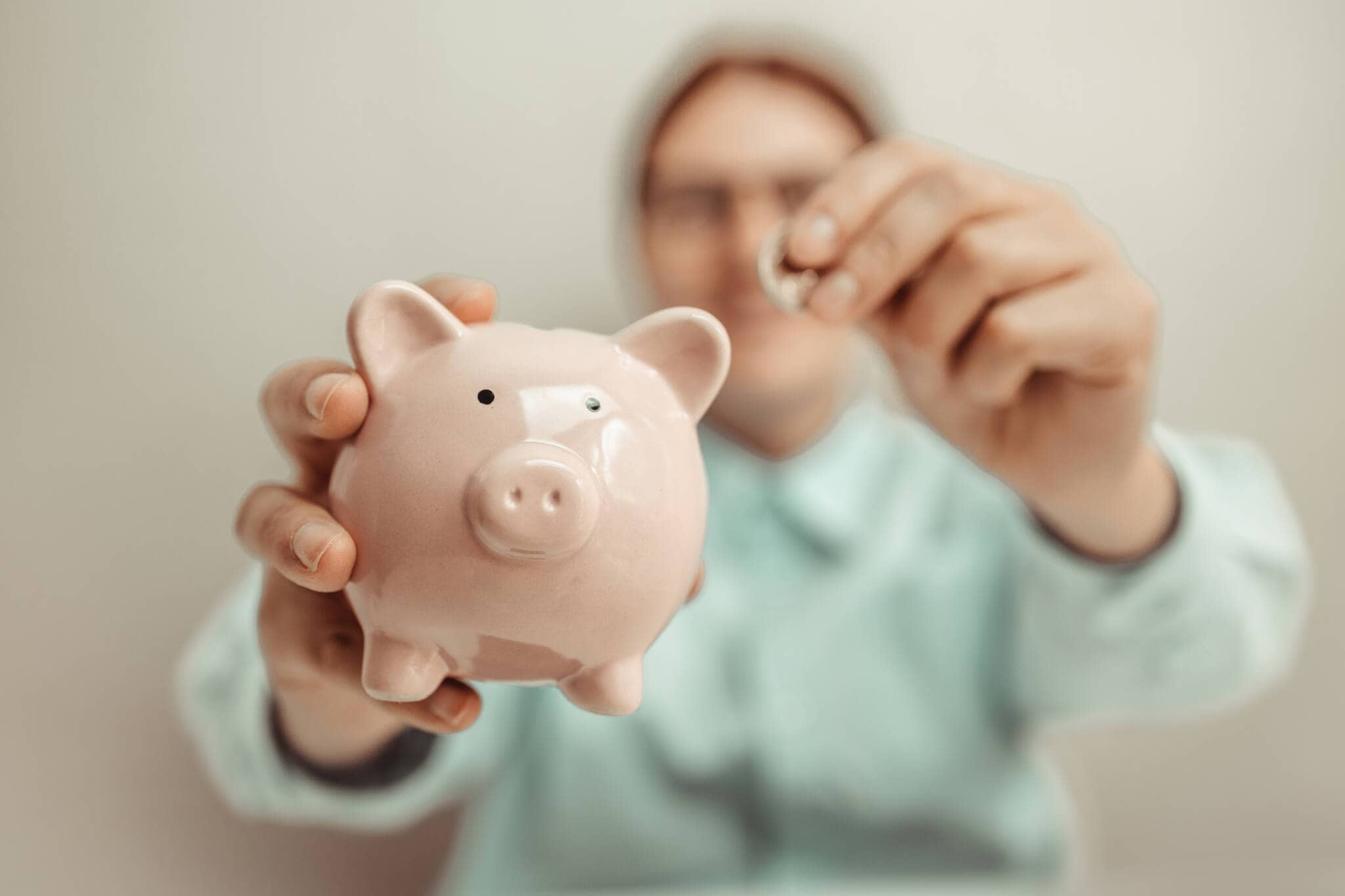 pessoa a tirar dinheiro do seu porquinho mealheiro que representa o PPR para pagar o seu crédito habitação