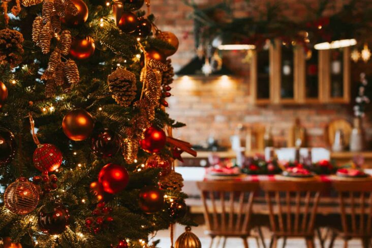 árvore de Natal em primeiro plano num ambiente de cozinha e sala com uma mesa da consoada preparada, celebrando o Natal sem desiquilibrar orçamento familiar
