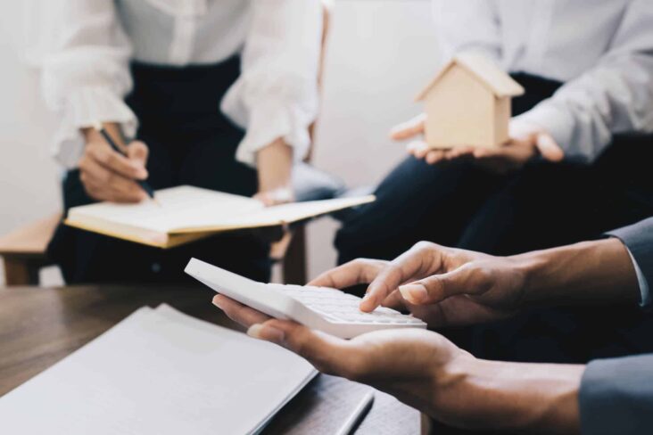 casal a fazer contas com a ajuda de uma especialista para ver qual é a prestação mensal que podem pagar por uma casa
