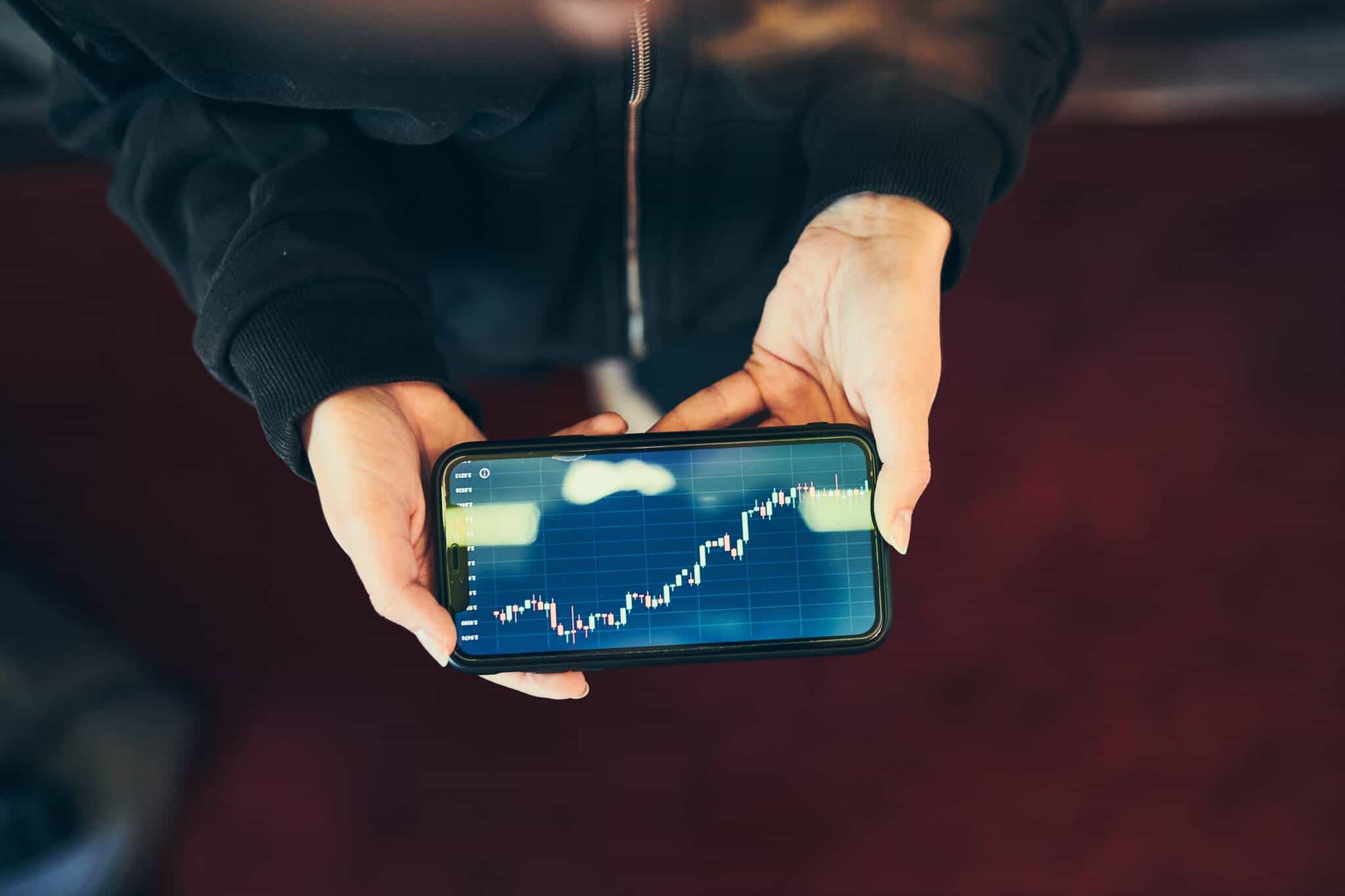 pessoa a analisar investimentos no smartphone